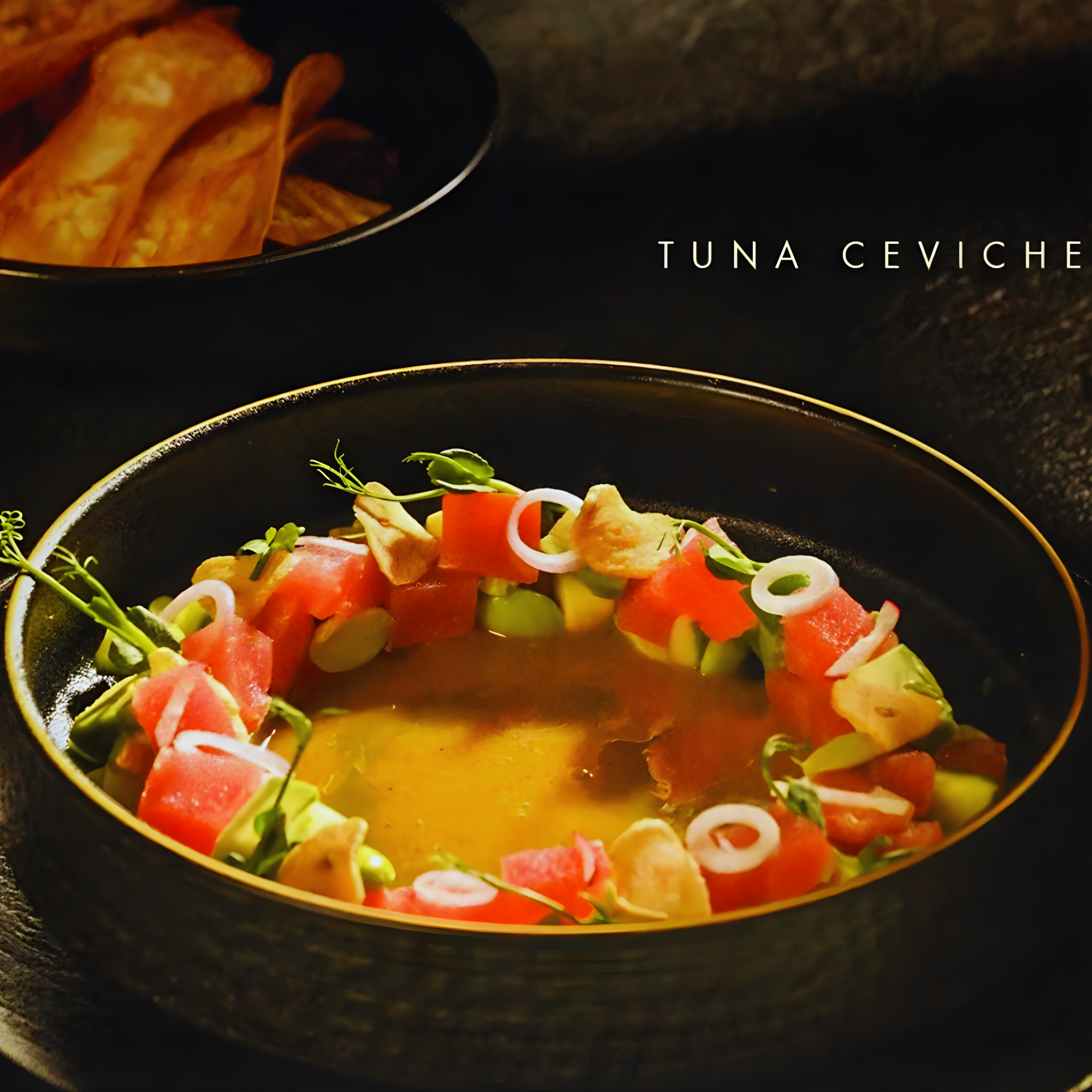 Close-up of a bowl of tuna ceviche with diced vegetables, garnished with microgreens and served on a dark plate.