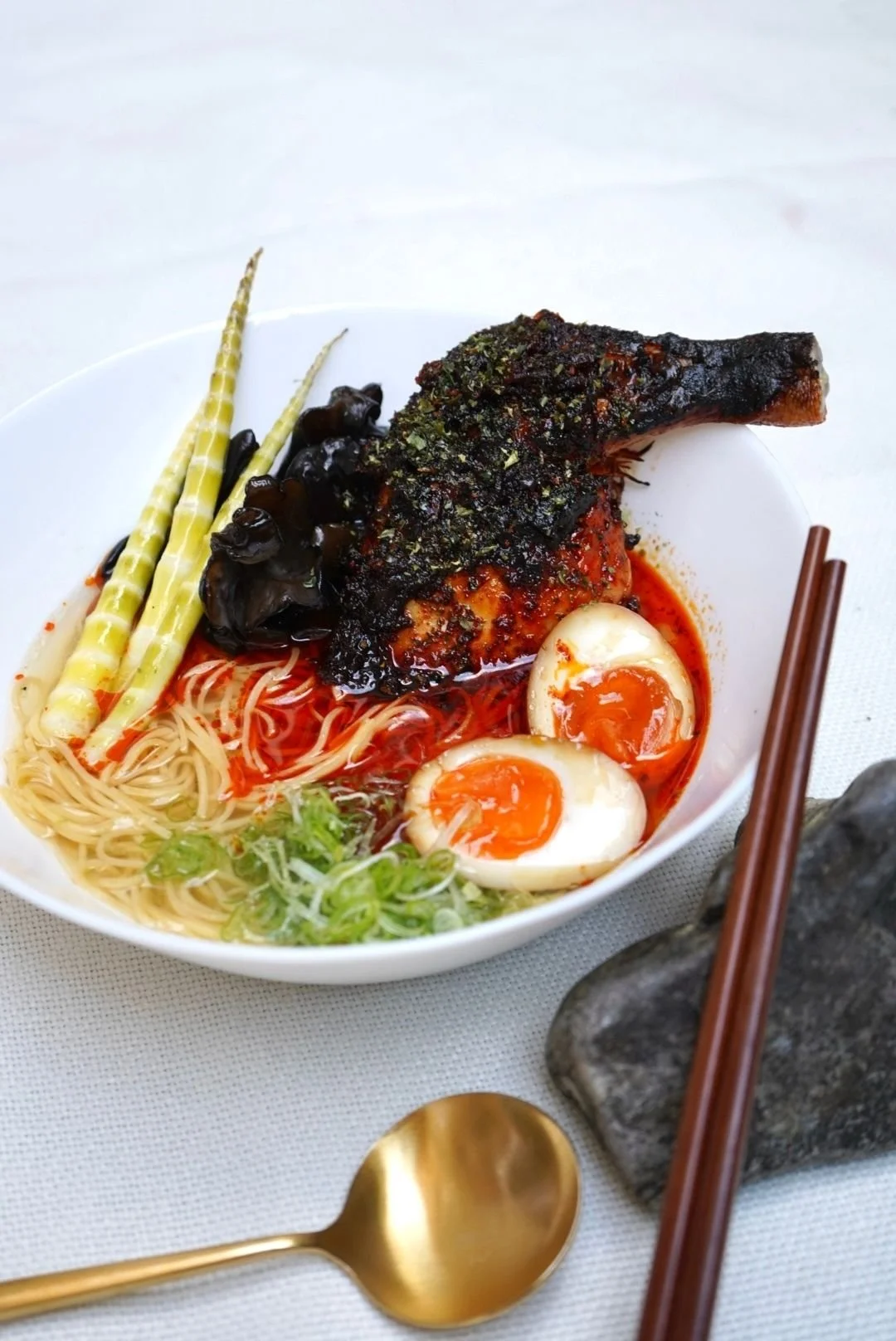 Close up of a bowl of food containing heritage chicken with sauce and other extras, along with a copper spoon — Kilted Chicken by Chef Rodney Wages