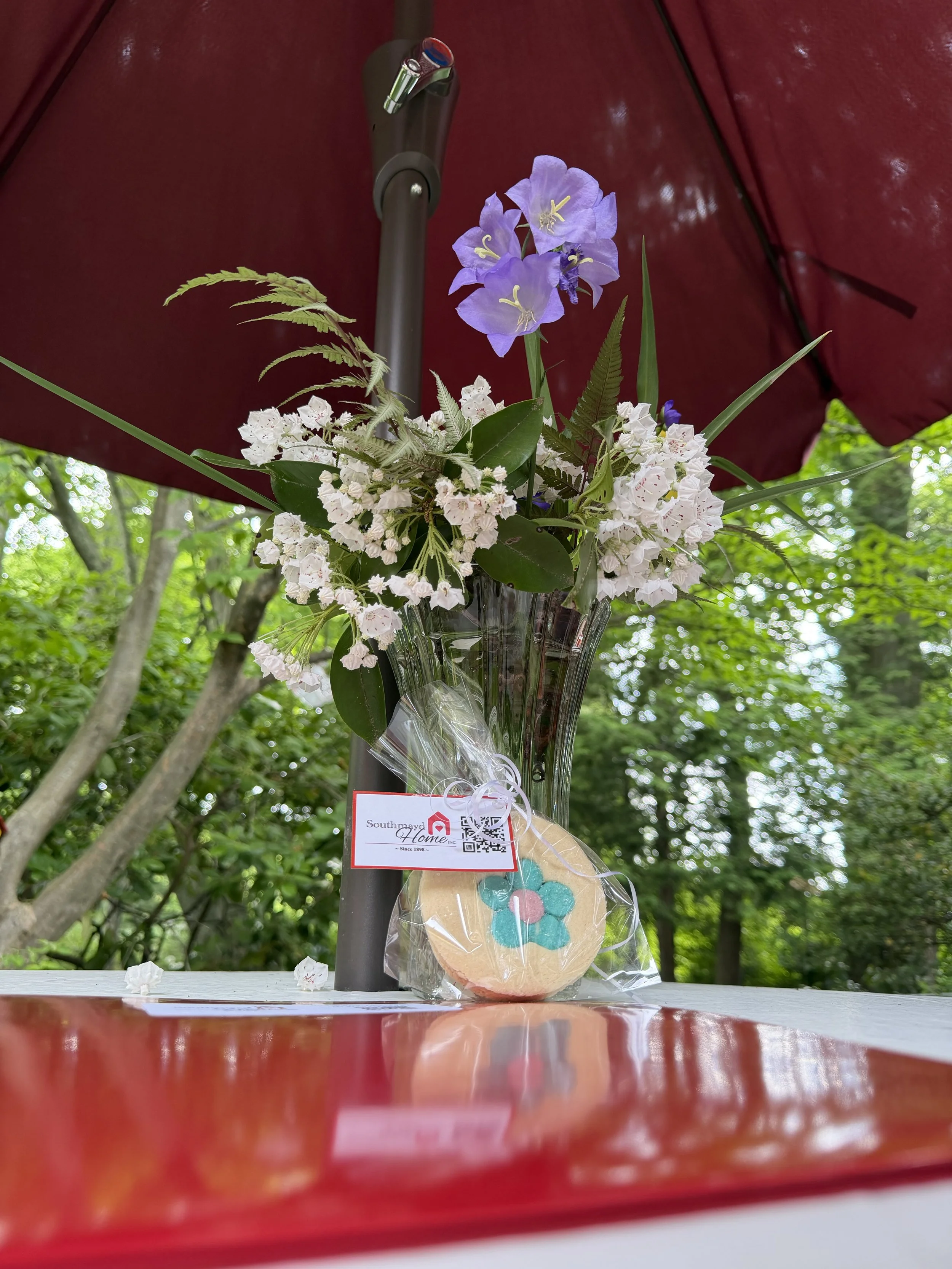 Southmayd home open house in the garden park. Flowers, cookie, and folder with info
