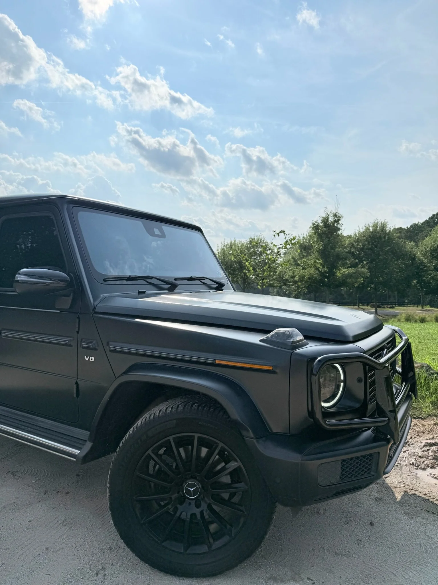 Front three-quarter view of matte black Mercedes G-Wagon parked outside Athens wedding venue