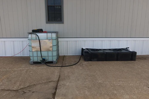 Fresh water and waste tanks set beside a job site office trailer
