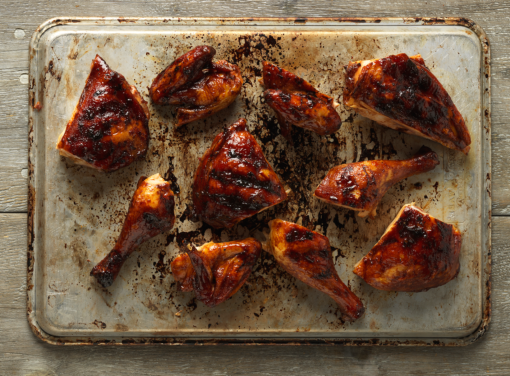 Hill Country barbecue chicken pieces arranged on a metal baking tray.
