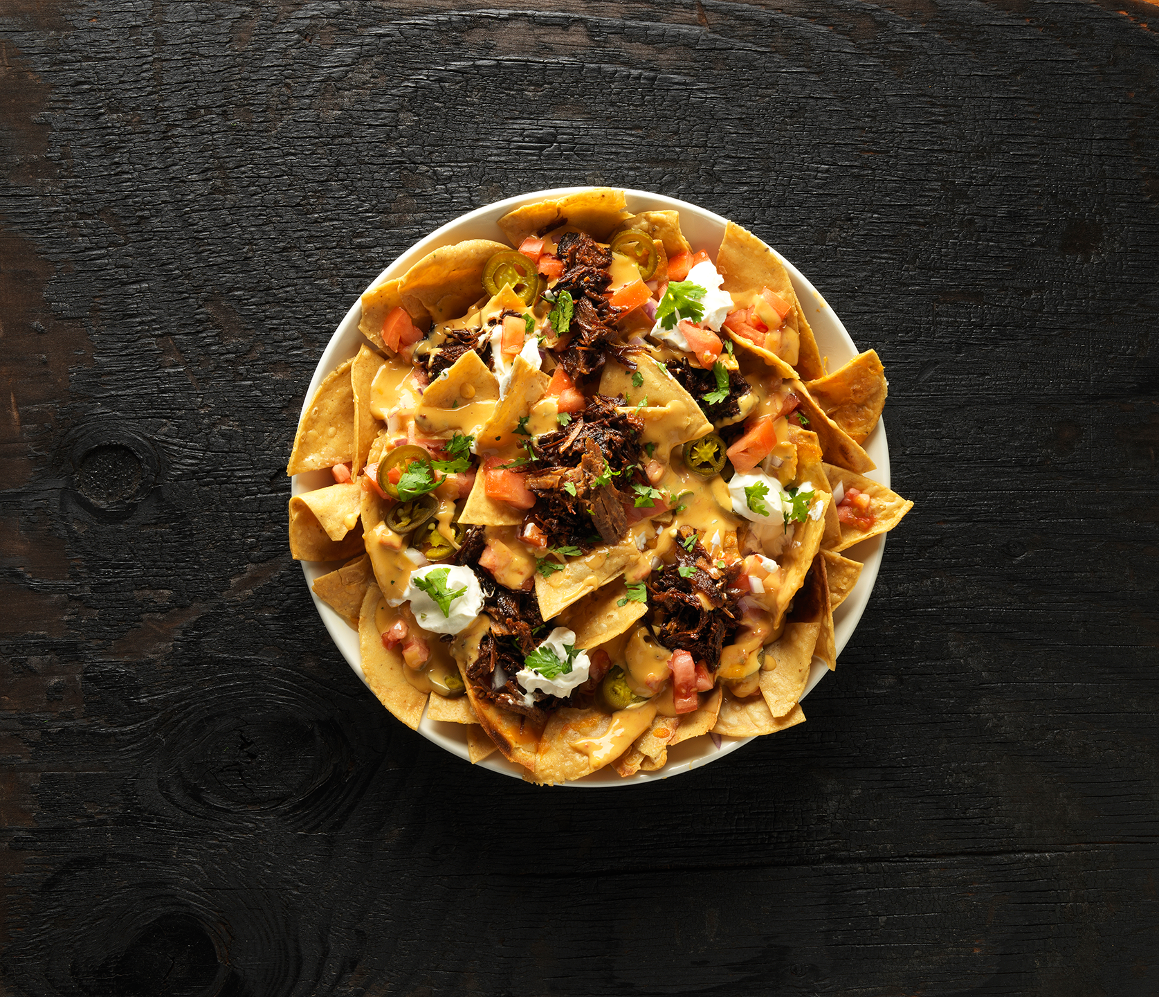 Hill Country loaded barbecue nachos topped with cheese, meat, jalapeños, tomatoes and sour cream.