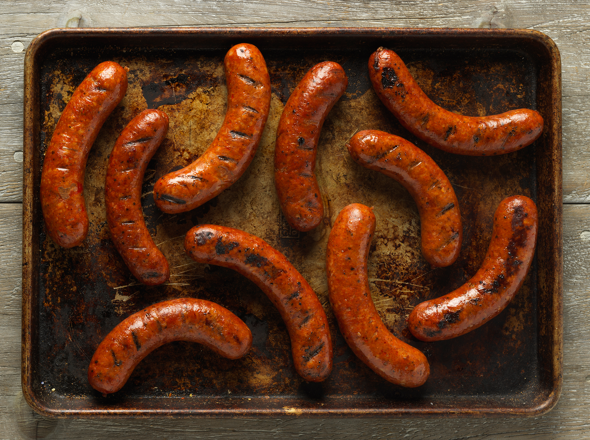 Hill Country sausages photographed on a well-used metal baking tray.