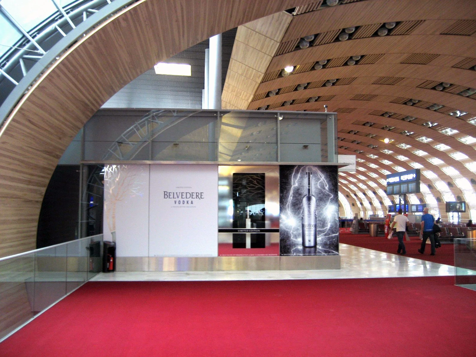 Wide view of the Belvedere Vodka retail installation beneath the curved terminal roof at Charles de Gaulle Airport.