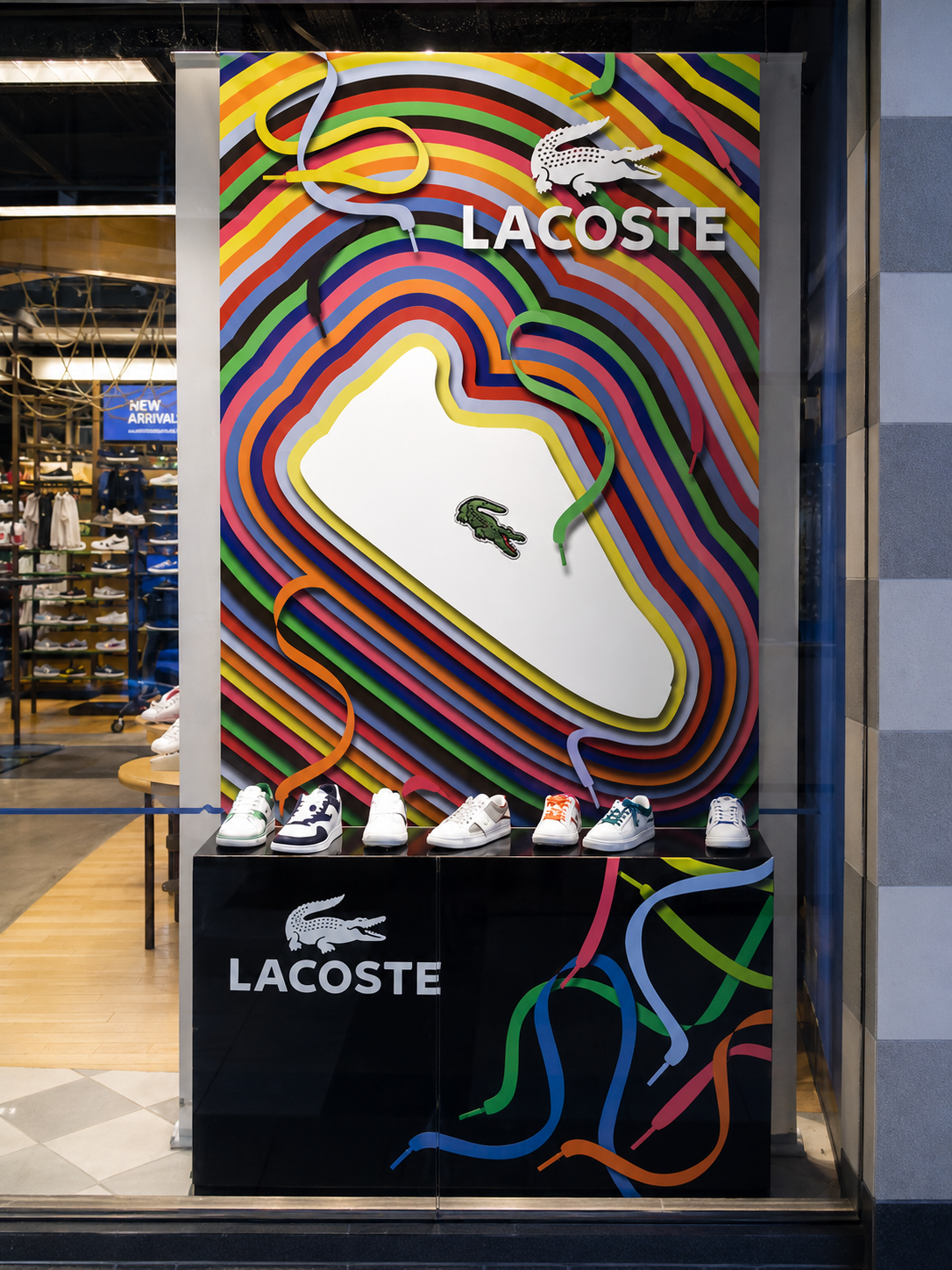 Lacoste Finish Line window installation with rainbow contour graphics and a branded shoe-display base.