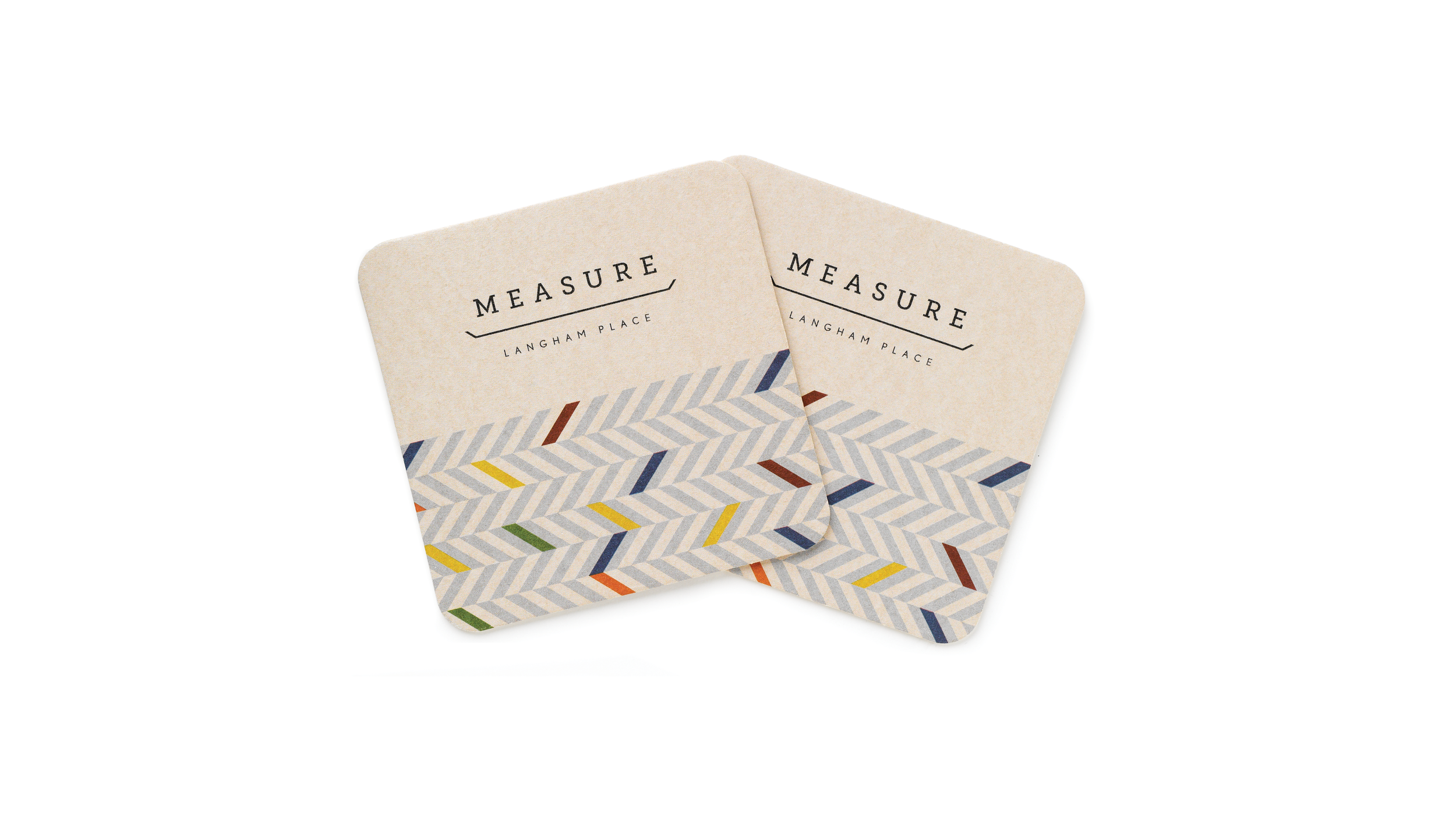 Two cream Measure Langham Place coasters with multicolored herringbone patterning.