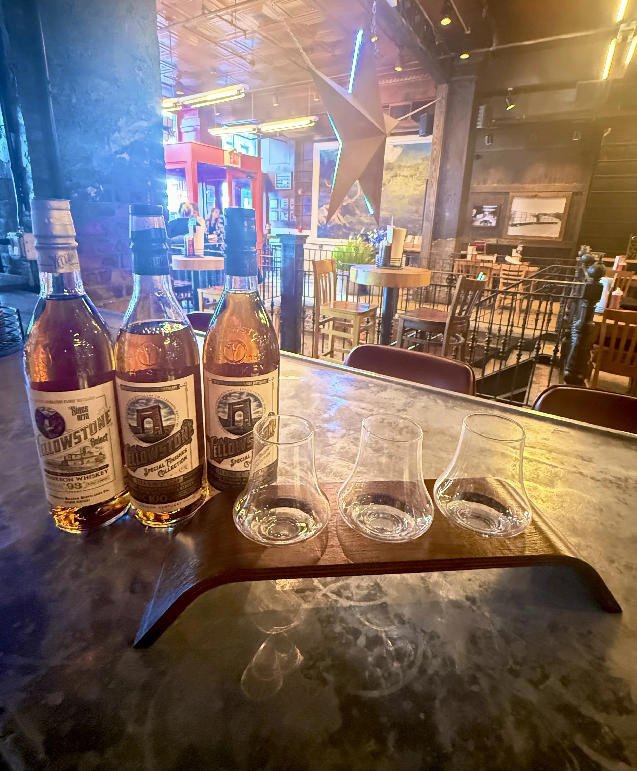 Source photograph of Yellowstone whiskey bottles and empty tasting glasses at the Hill Country bar.