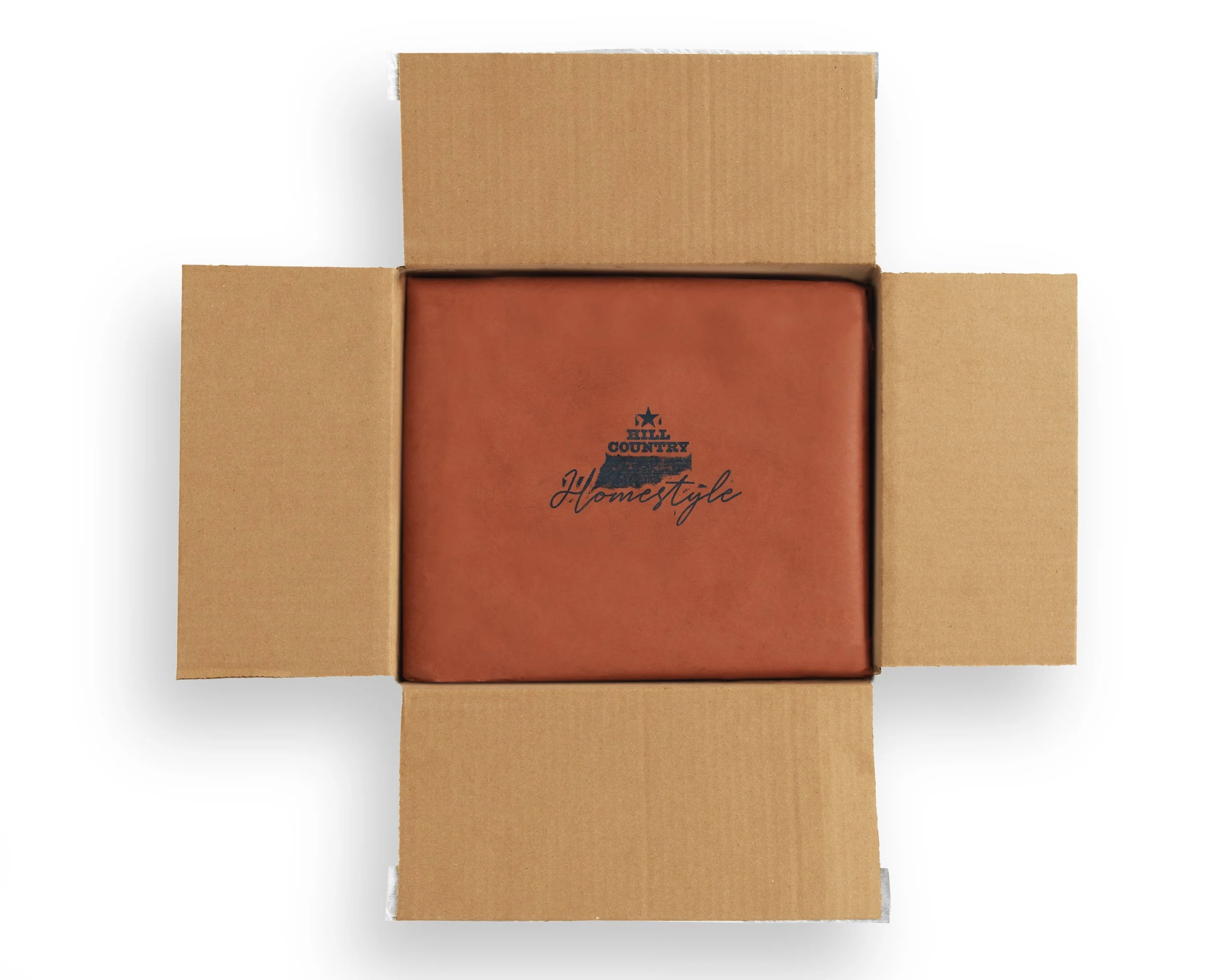 Open Hill Country Homestyle shipping box with branded brown tissue paper covering the contents.