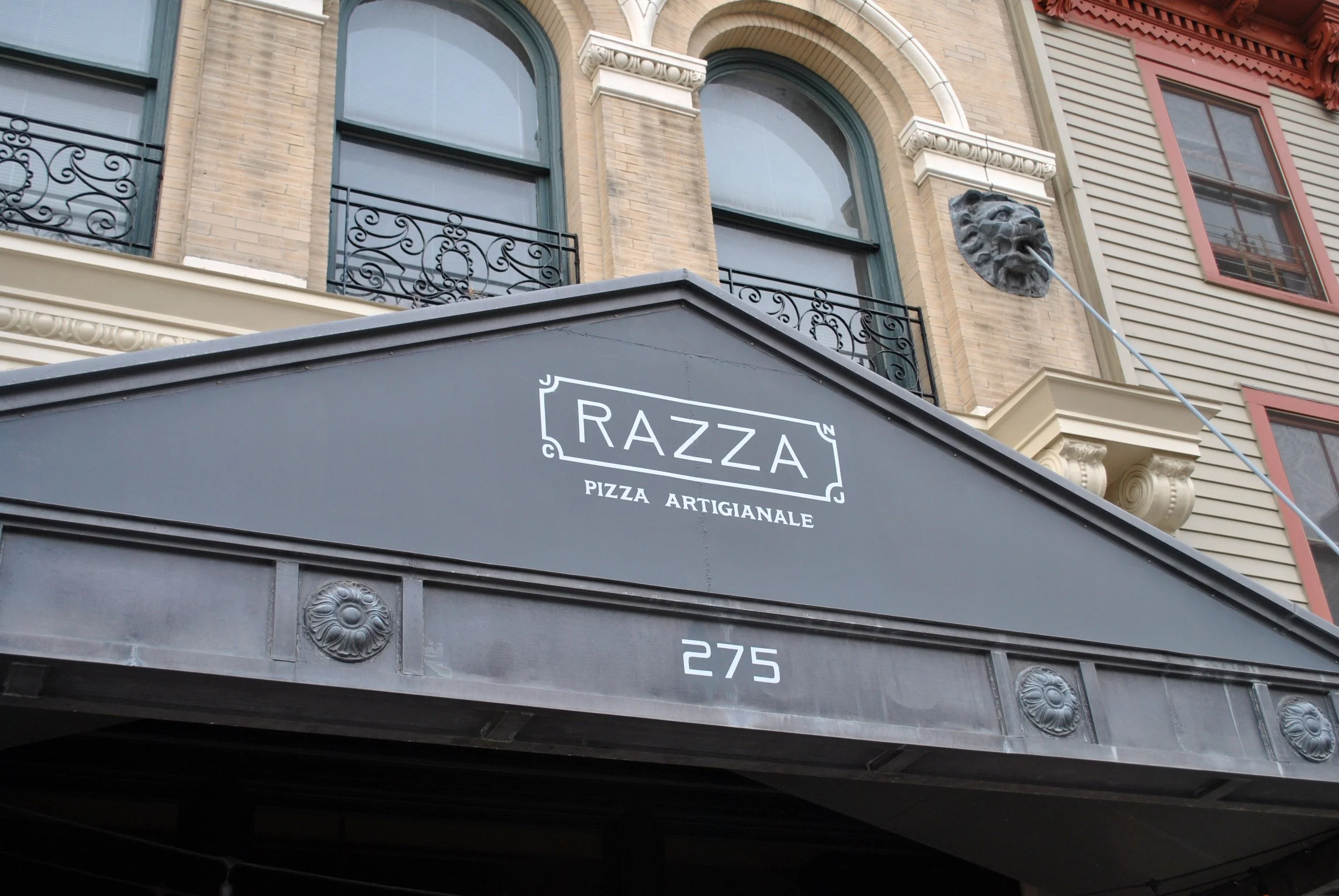 Razza Pizza Artigianale logo on the gray entrance canopy at 275 Grove Street.