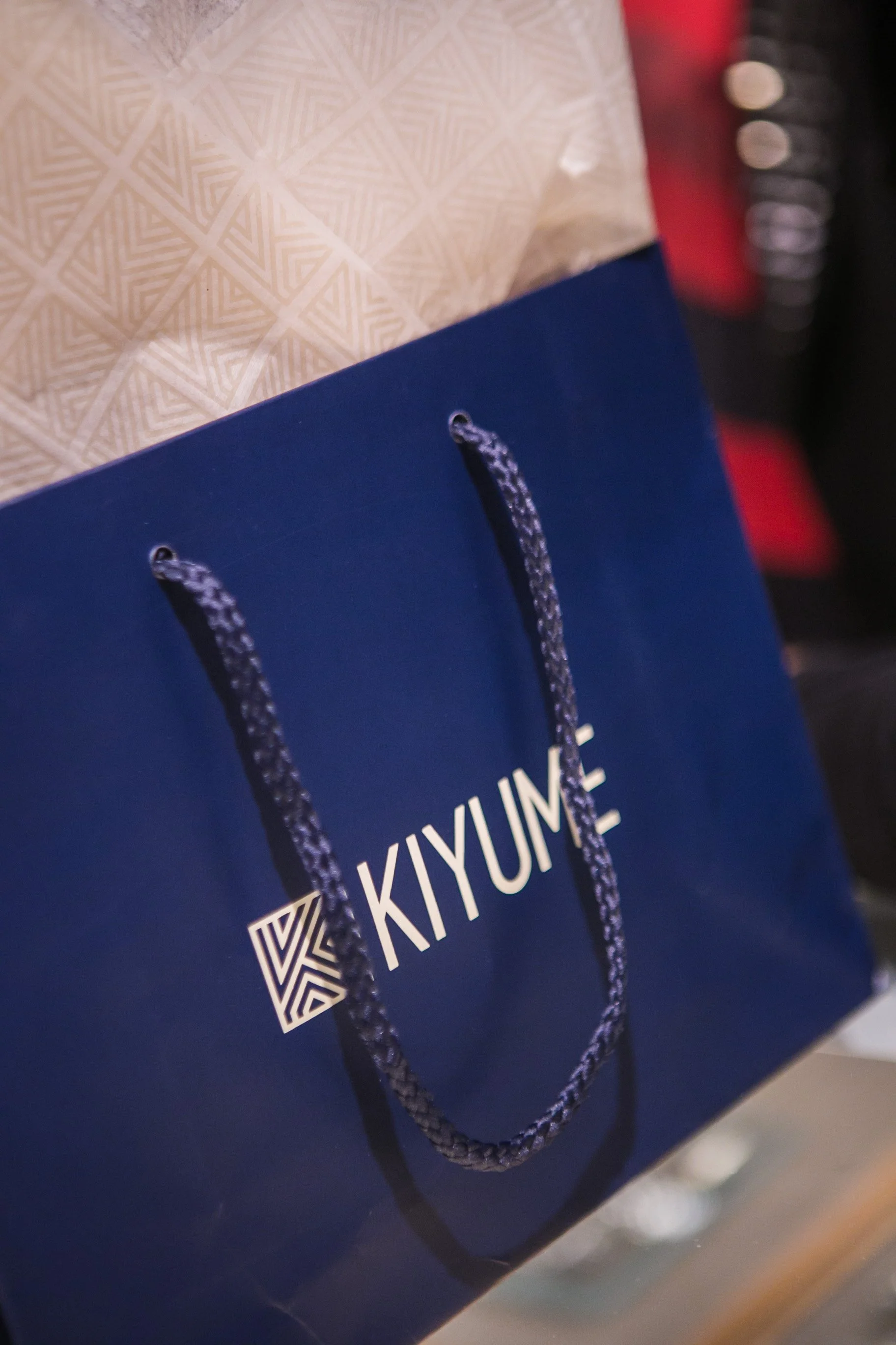 Navy Kiyume shopping bag with white branding, rope handles and geometric-patterned tissue paper.