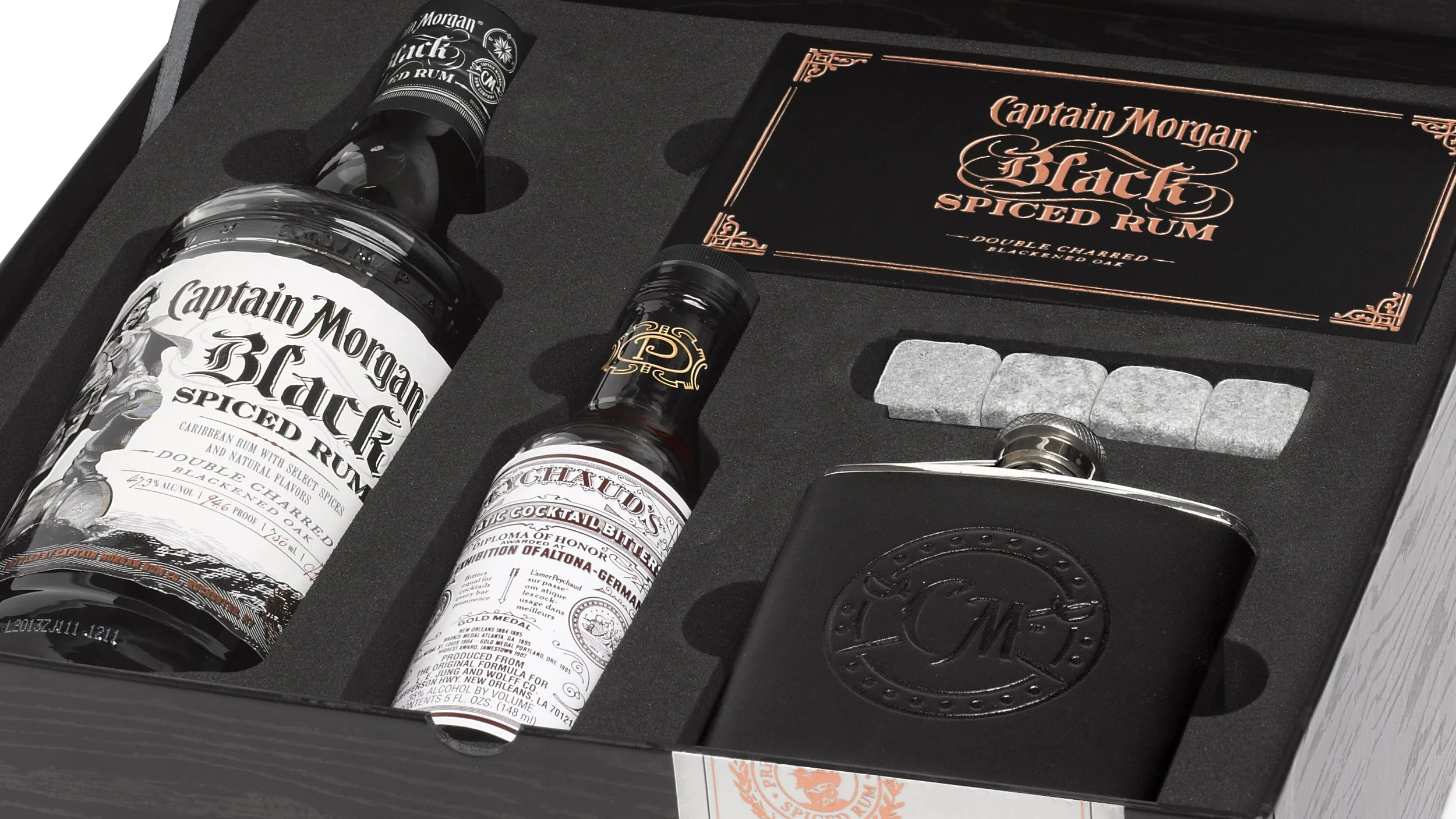 Detail of the Captain Morgan Black trade kit showing rum, bitters, chilling stones, a flask and the copper-lettered book.