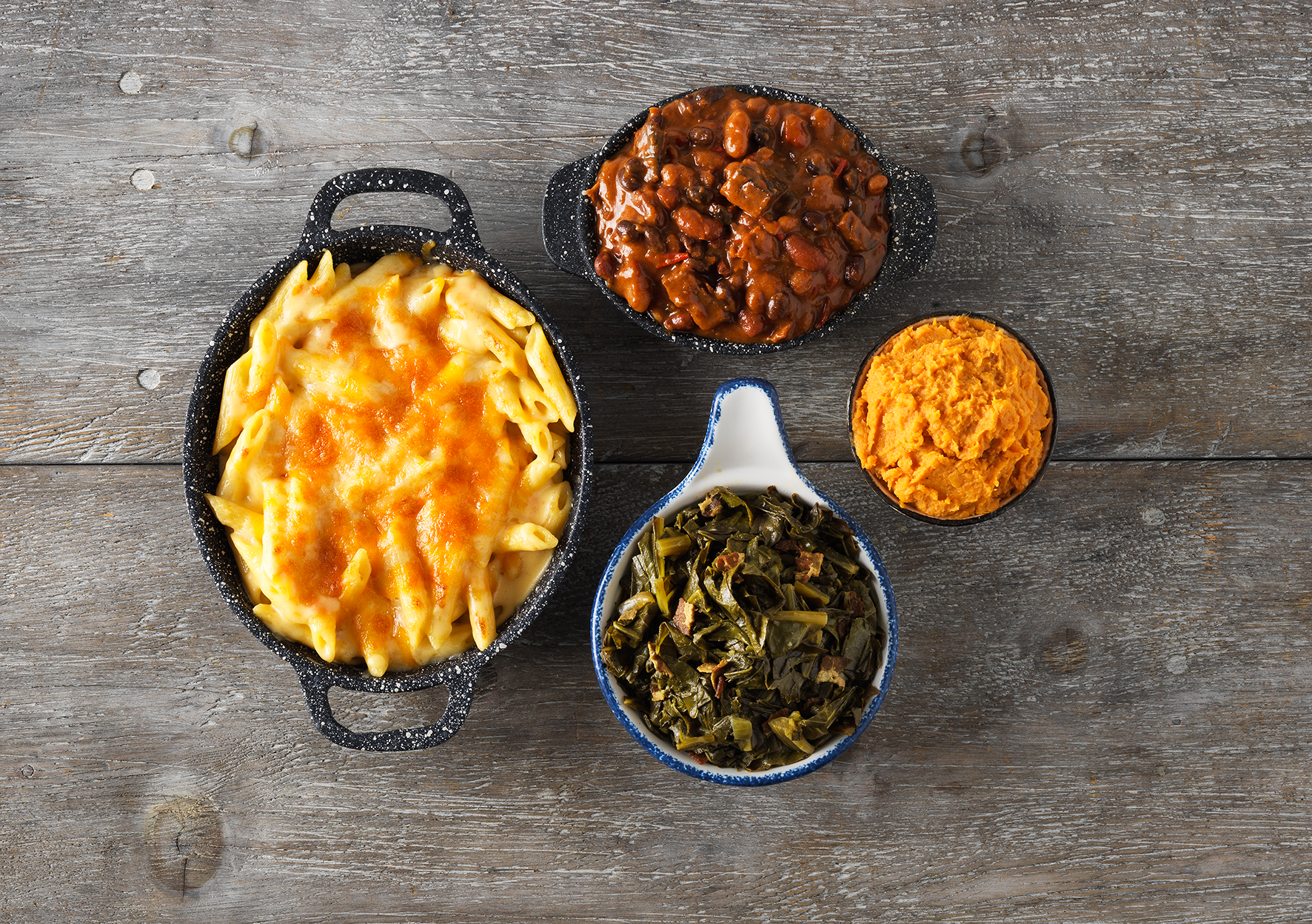 Hill Country side dishes, including macaroni and cheese, beans and greens, photographed from above.