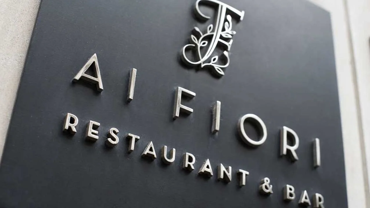 Ai Fiori exterior restaurant sign with raised metallic lettering and a floral monogram.