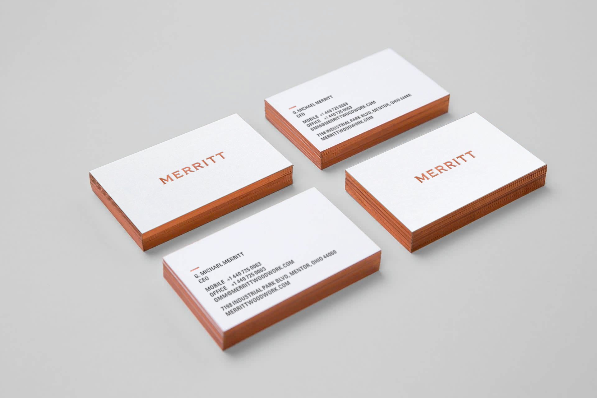 Merritt business cards with copper-colored wordmarks and edges, arranged on a pale gray surface.