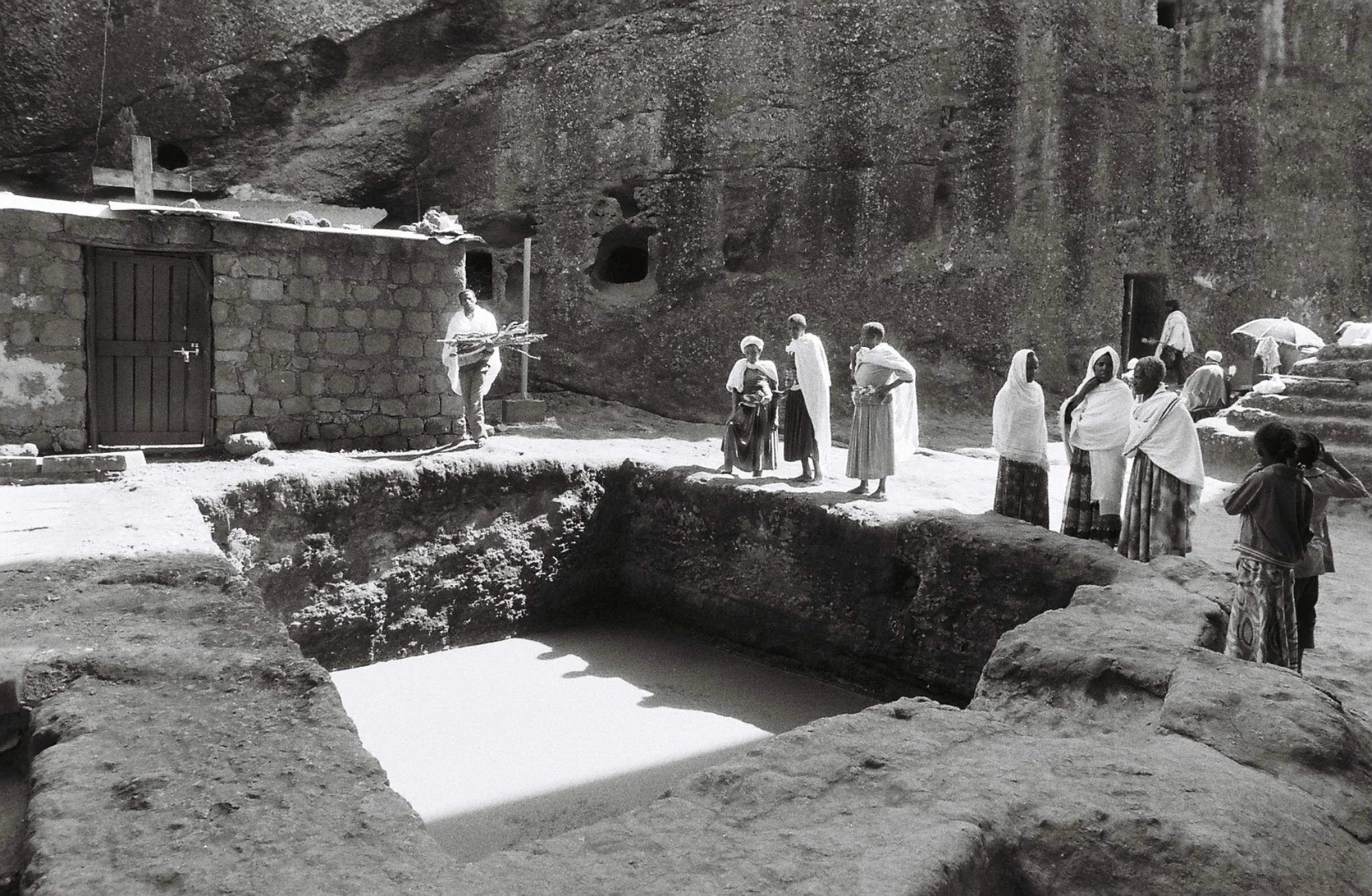 Pilgrims chat quietly near a half-filled pool of water outside the churches of Lalibela.
