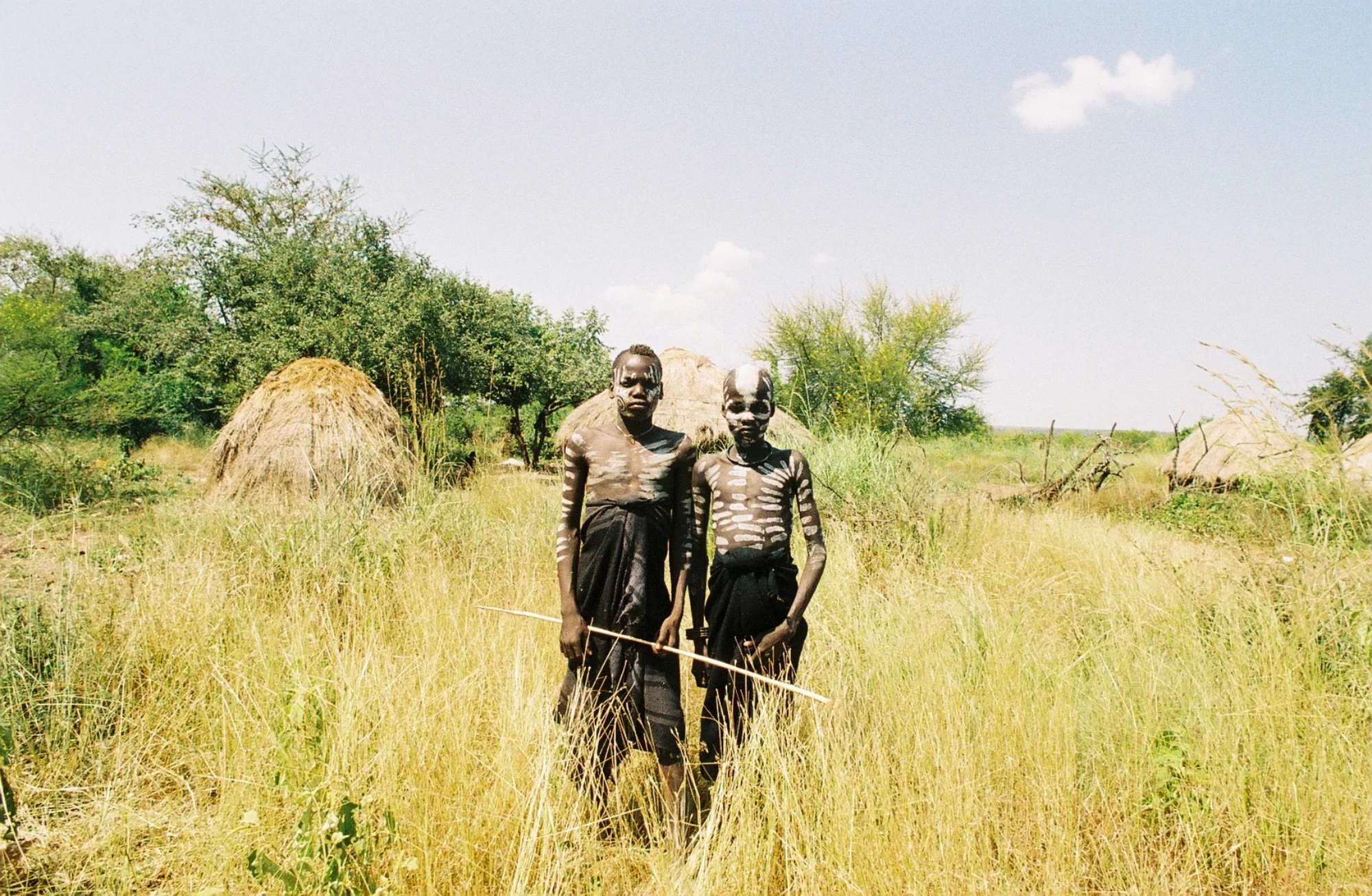 Two young members of the Mursi tribe in Ethiopia's Omo Valley stand stoically together. The community is becoming used to seeing tourists, and intentionally "dress-up" to capitalize on photo opportunities. As more tourists travel into the tribal regi