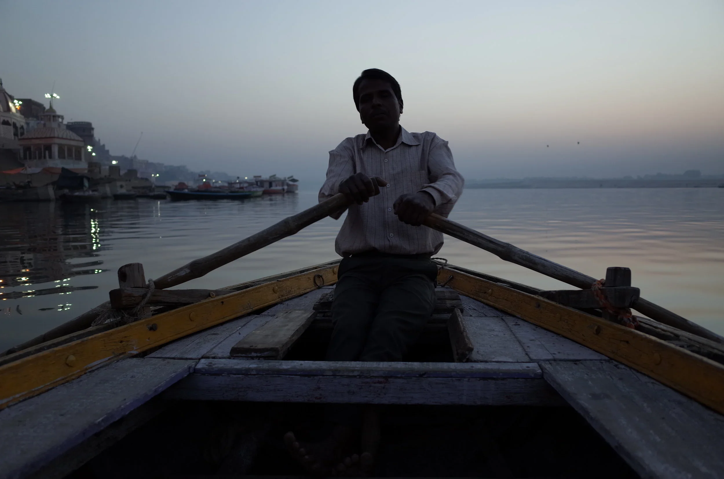 A guide rows quietly along the Ganges river at sunrise in Varanasi, India.