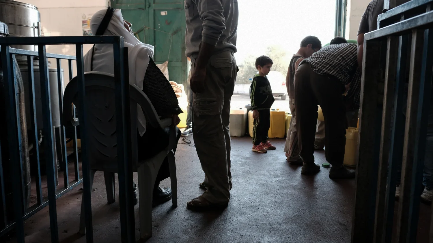 The sun is starting to set, but the activity at the olive press only builds. Farmers sit next to their bottles waiting to be weighed and make payment in olive oil in exchange for the processing.