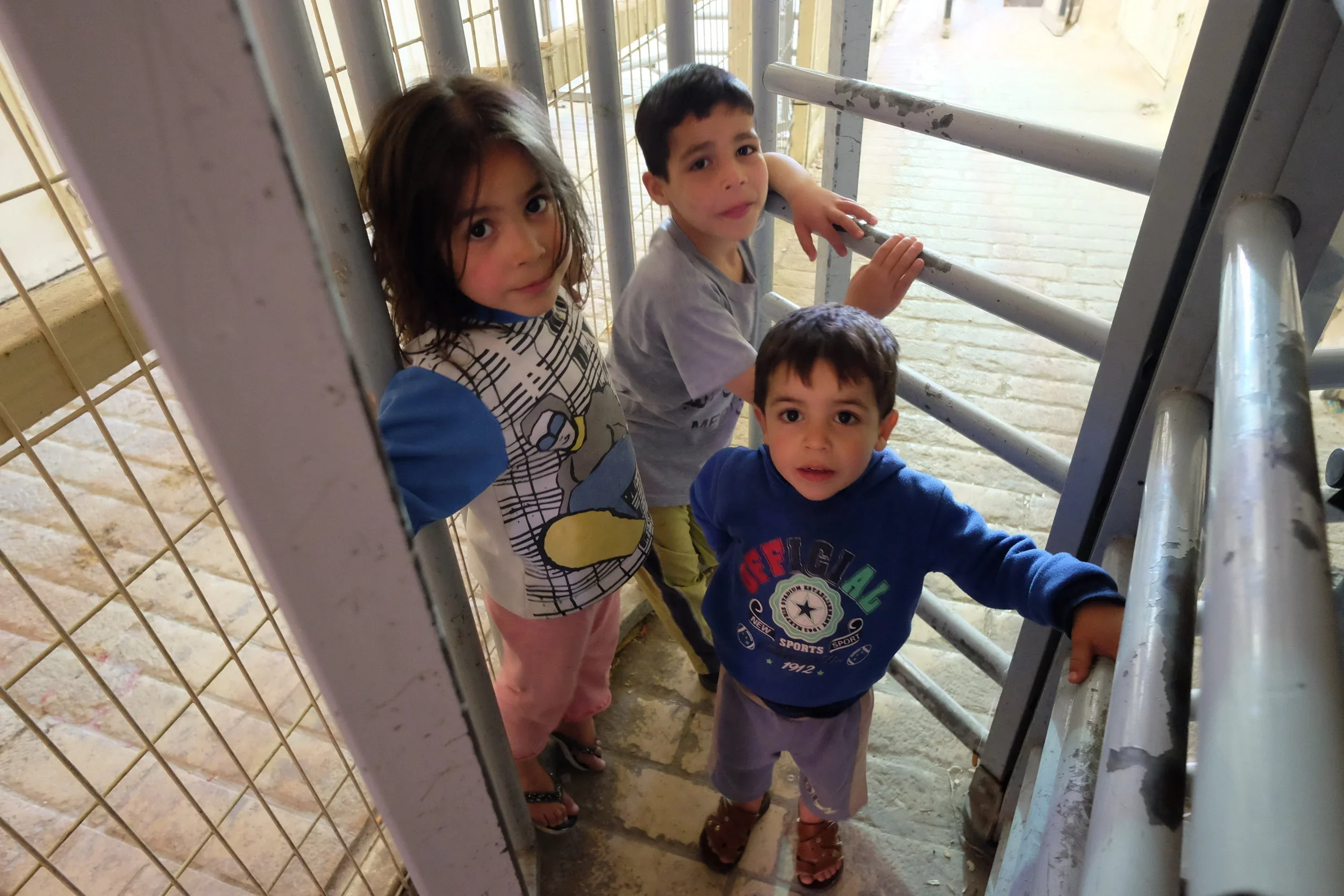 Three young Palestinian children wait to be granted entry through an H2 military check-point inside Hebron's Old Quarter. - April 29, 2017