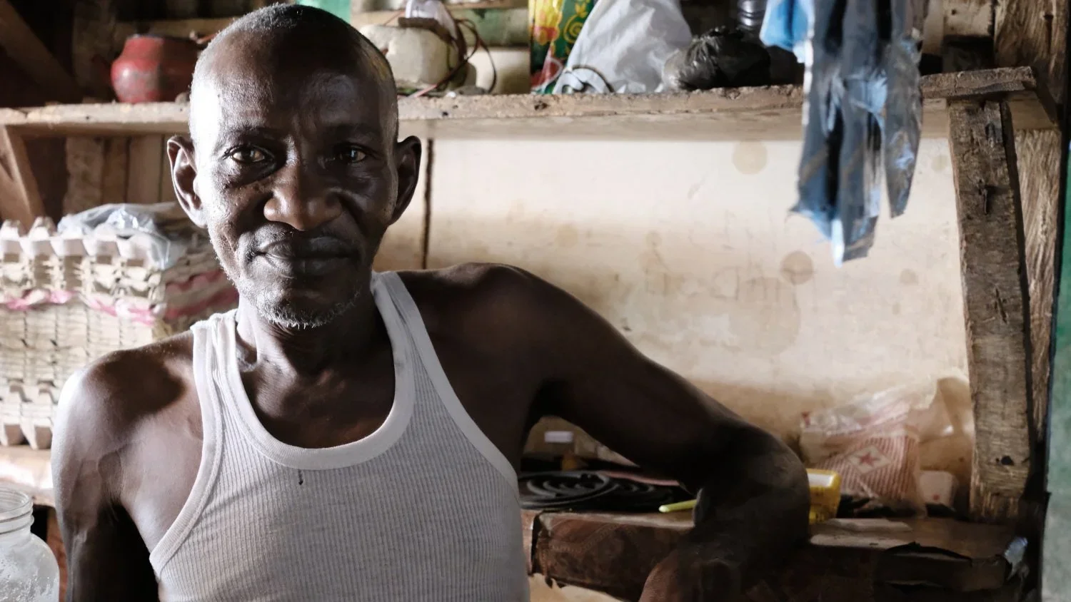 Mohamed Bah, 65, stands proudly inside his shop in the community of Kroo Bay. For 7-years he's been selling bread, coffee, milk and other goods to support his wife and five children. He's most proud that the income from his small business can fund hi