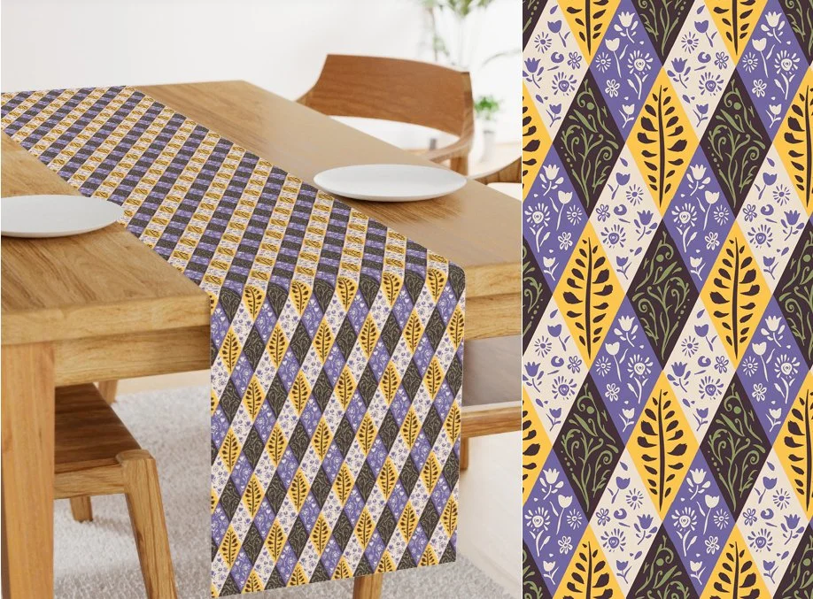 A wooden dining table with a purple, black, yellow, and white patterned table runner, along with two empty white plates. The table is in a bright room with a chair and a plant in the background.