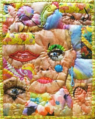 Colorful quilt with embroidered and appliqued abstract faces and patterns.