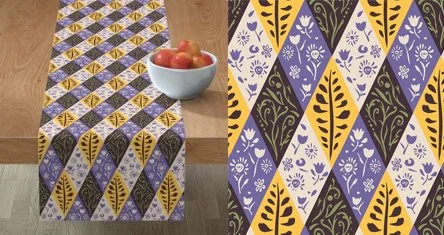 Tablecloth with geometric pattern in purple, yellow, and white on a wooden table with a bowl of apples.