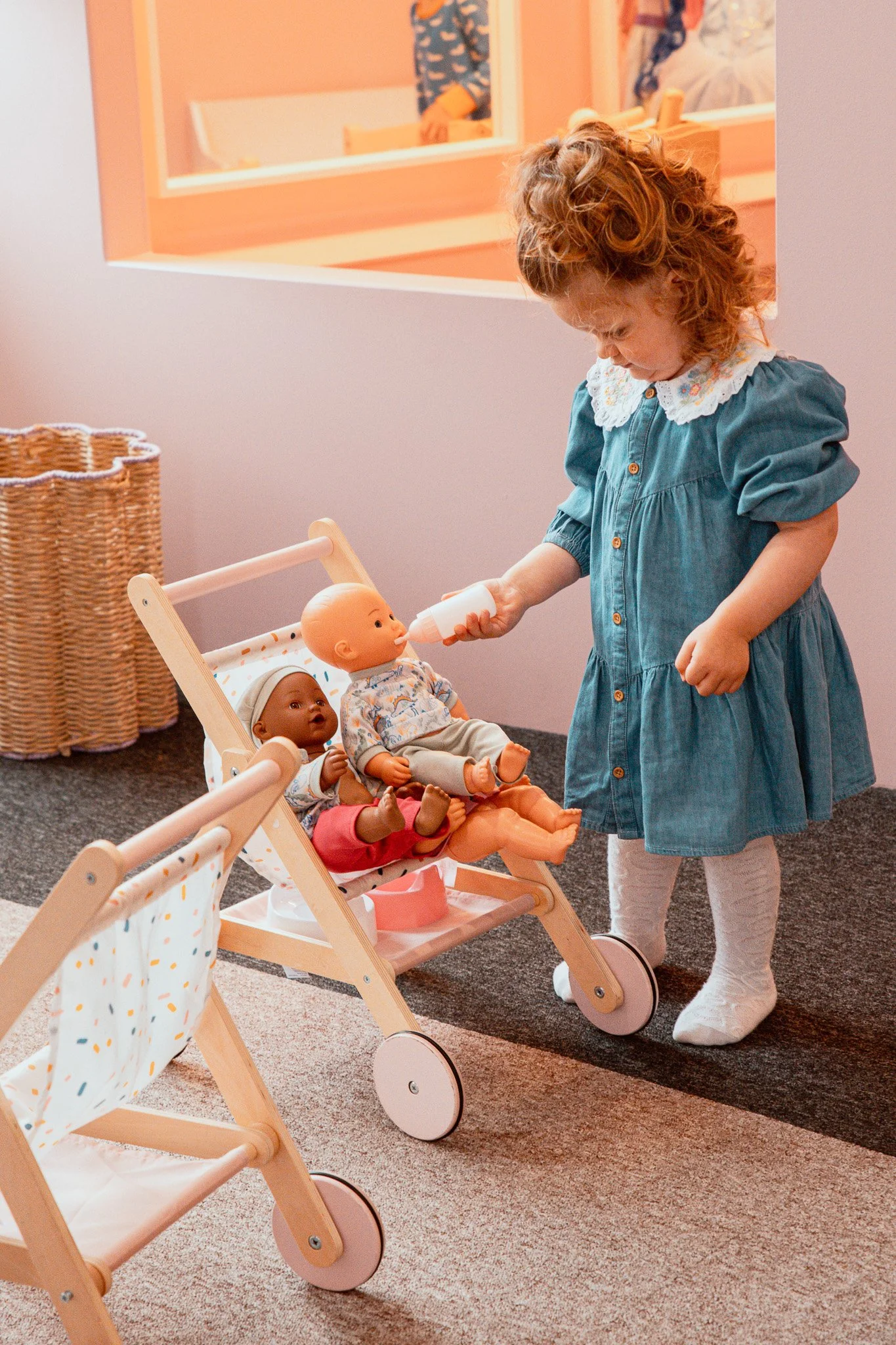 Little girl playing with dolls in a pushchair in our role play area.