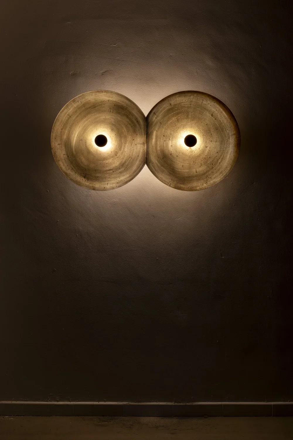Two circular ceiling lights with a warm glow mounted on a dark wall.