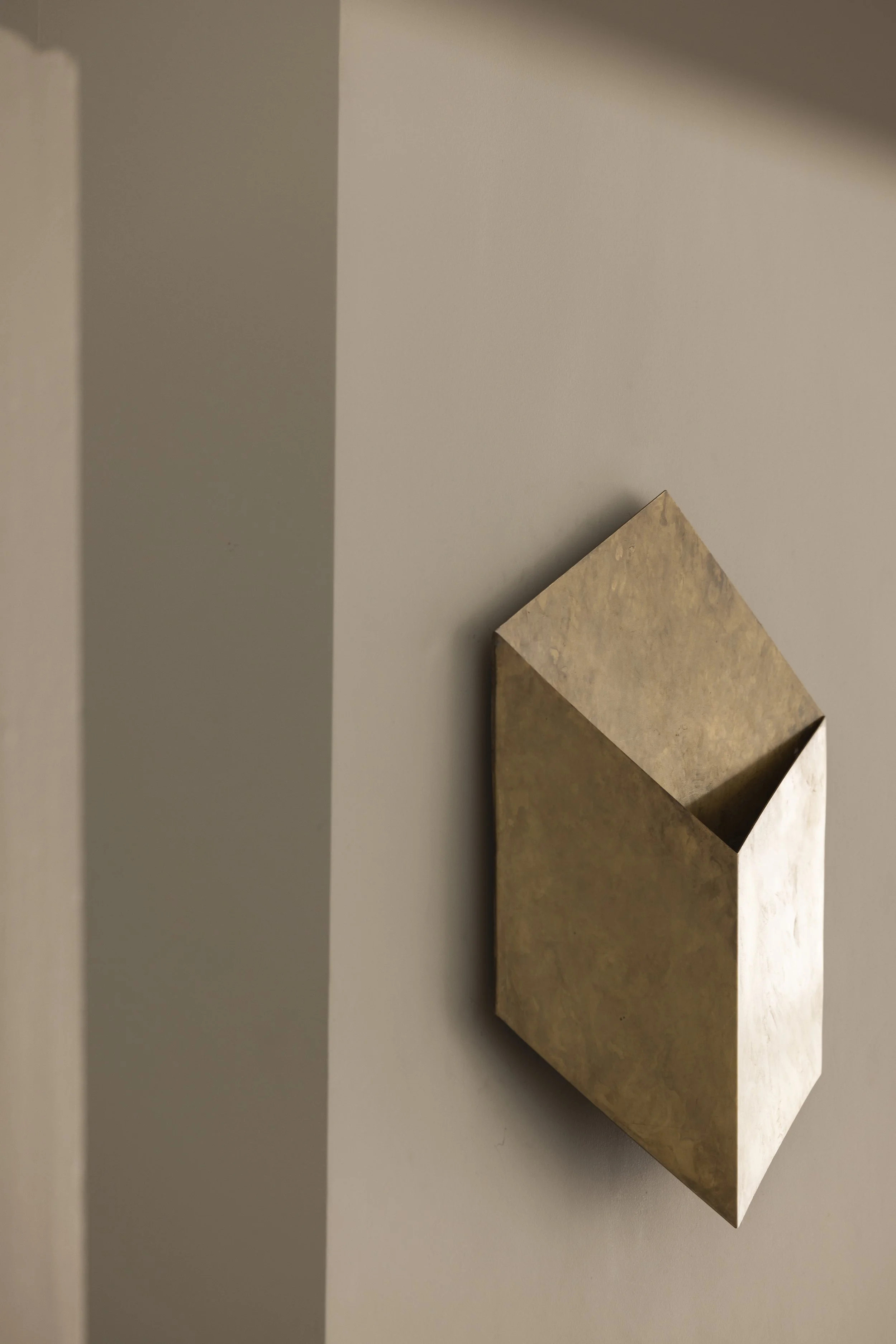 A beige hexagonal wall-mounted shelf with a marble-like finish on a gray wall.