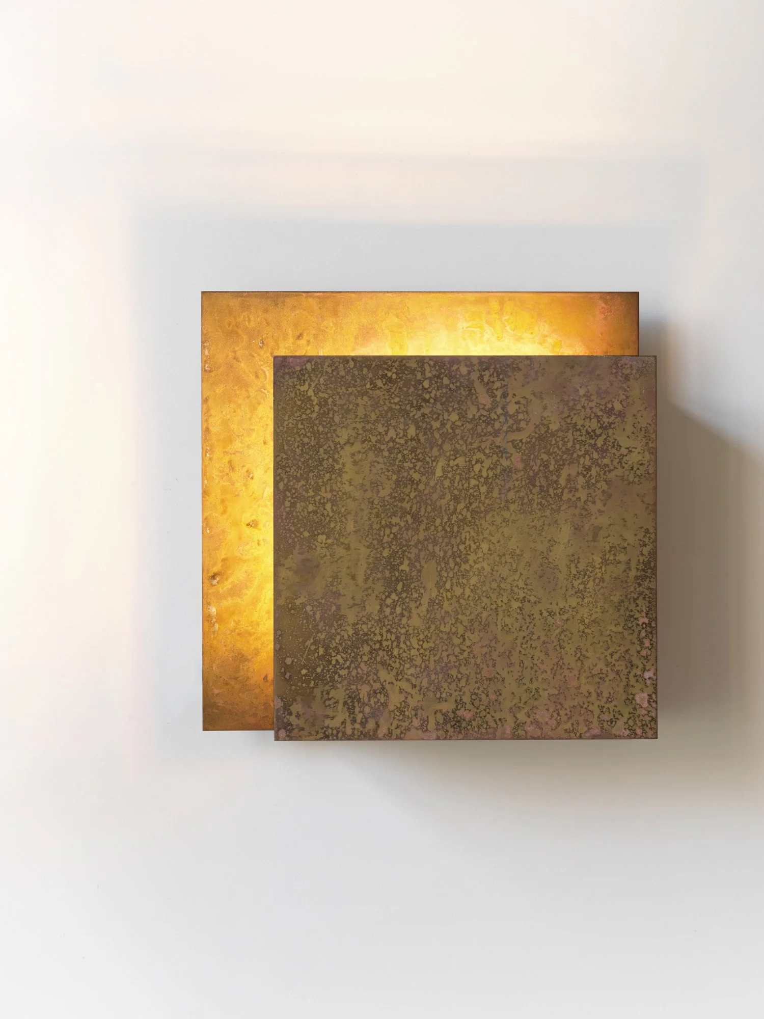 Three textured rectangular metal plates with different tones of gold and bronze, overlapping each other on a white background.