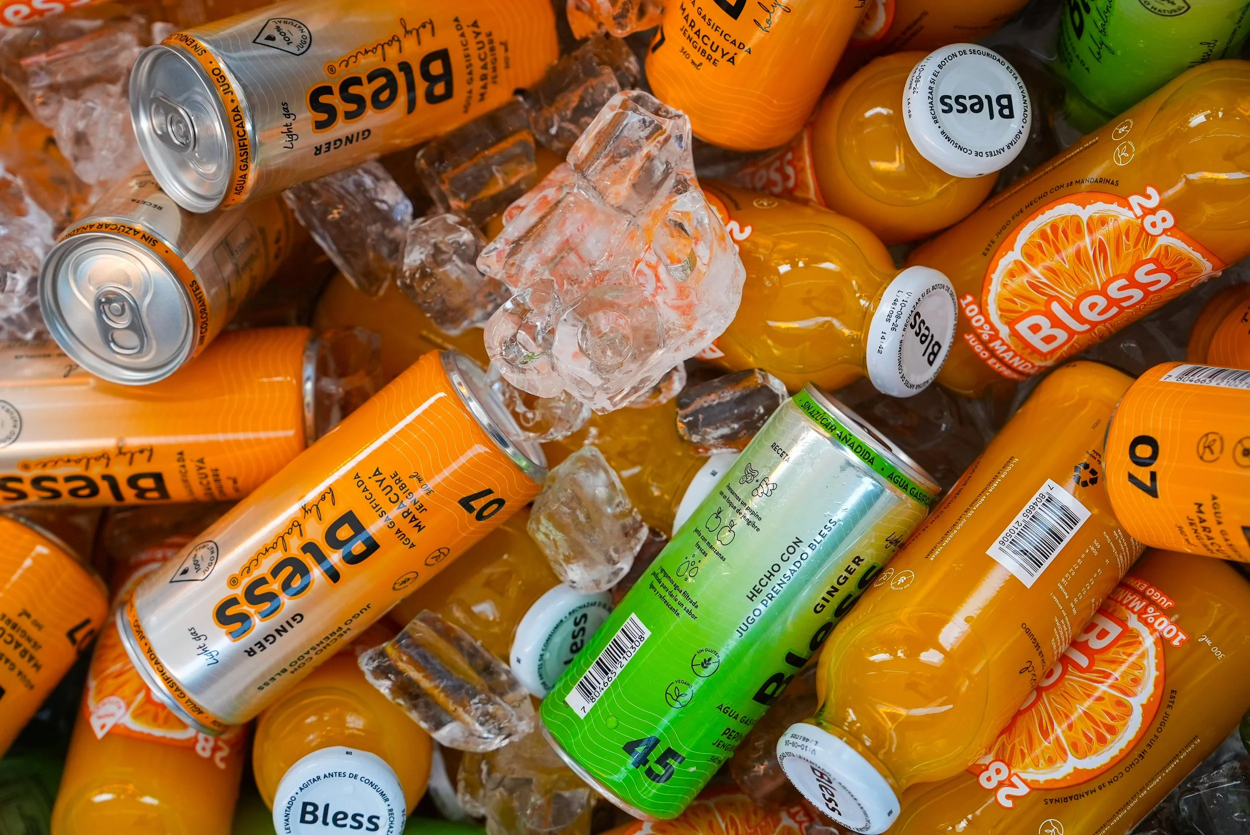 Latas de bebidas y botellas de jugo de mandarinas con hielo en un fondo de hielo picado.