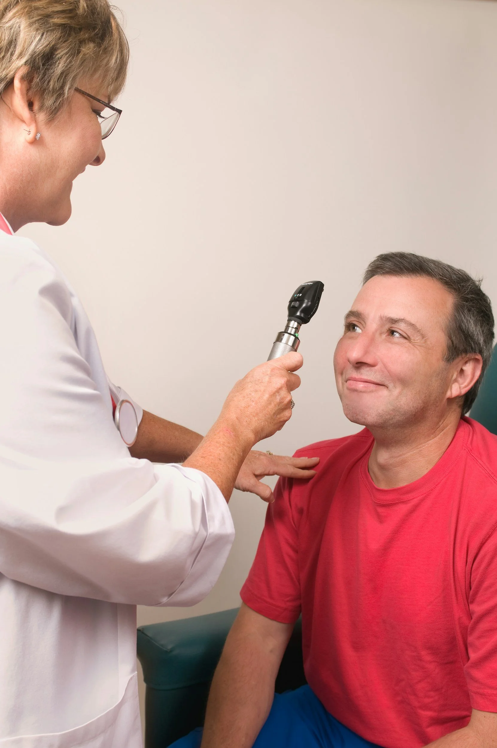 A healthcare professional using an otoscope to examine a man's ear during a medical appointment
