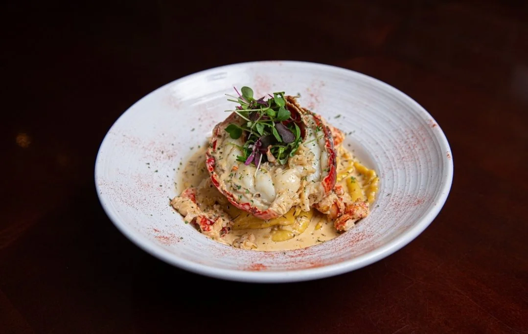 Lobster tail served on a plate with pasta, garnished with microgreens.