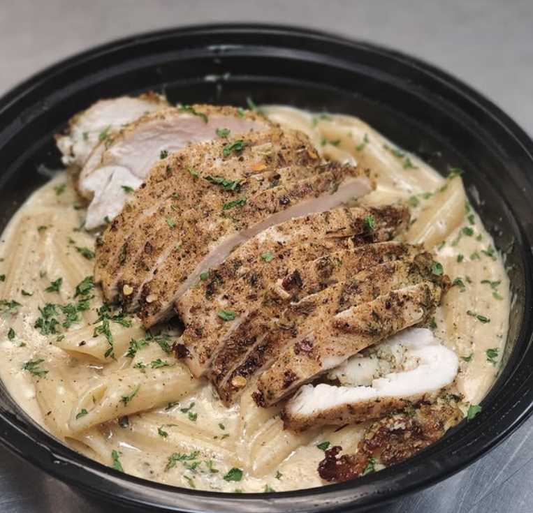 Creamy pasta dish with sliced herb-seasoned grilled chicken breast and chopped parsley.