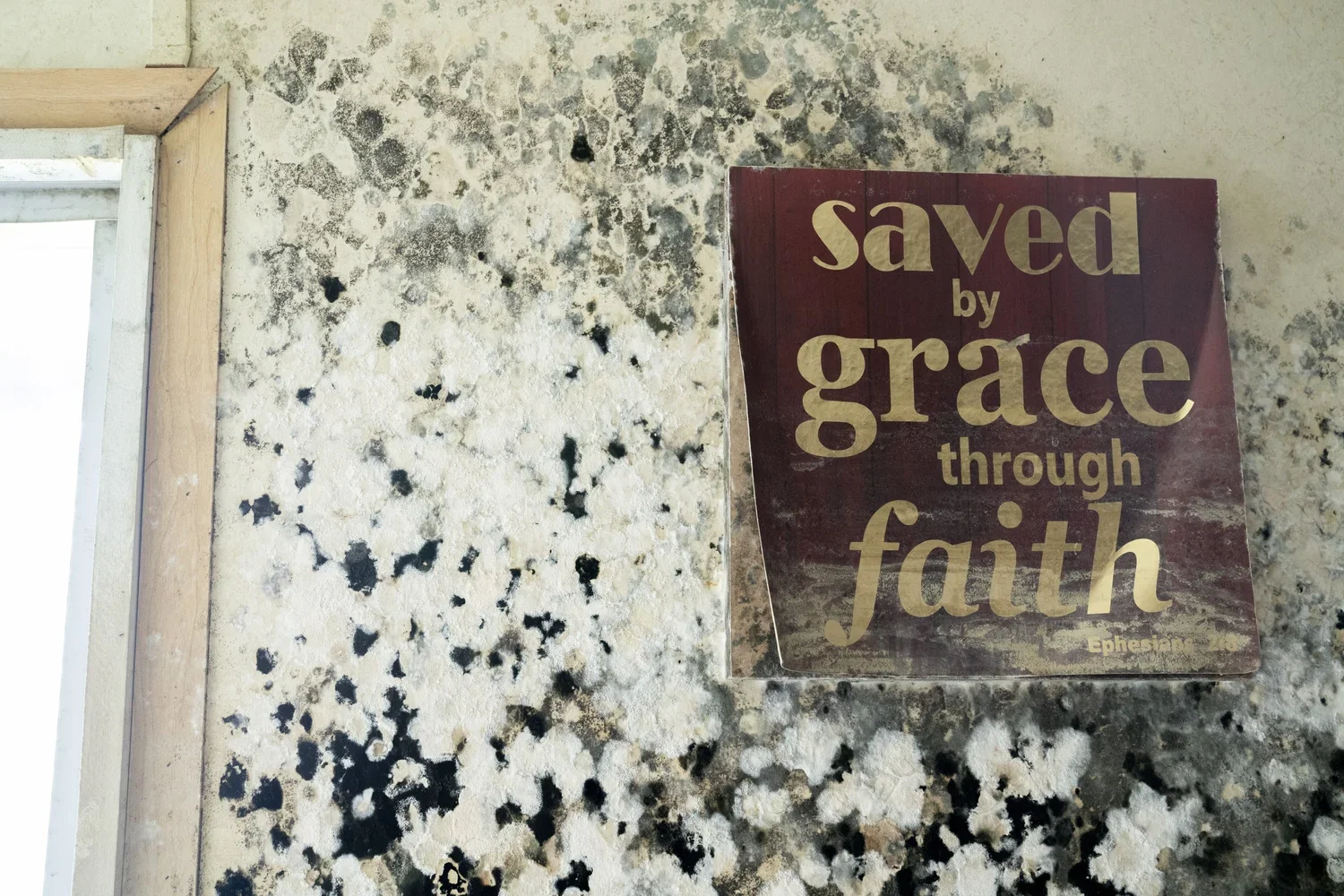A sign on a speckled stone wall reads 'saved by grace through faith' with a reference to Ephesians at the bottom.