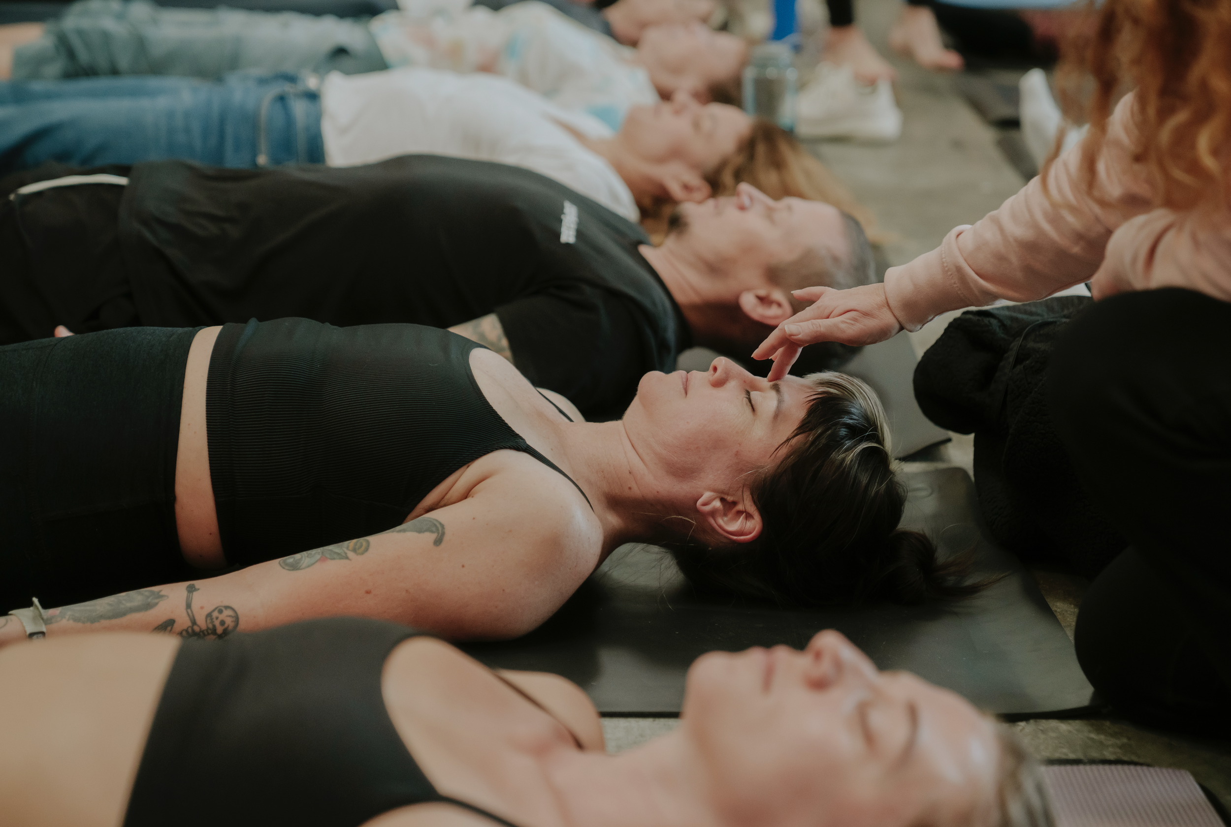 People lying on the floor with their eyes closed, some receiving hands-on healing or emotional support.