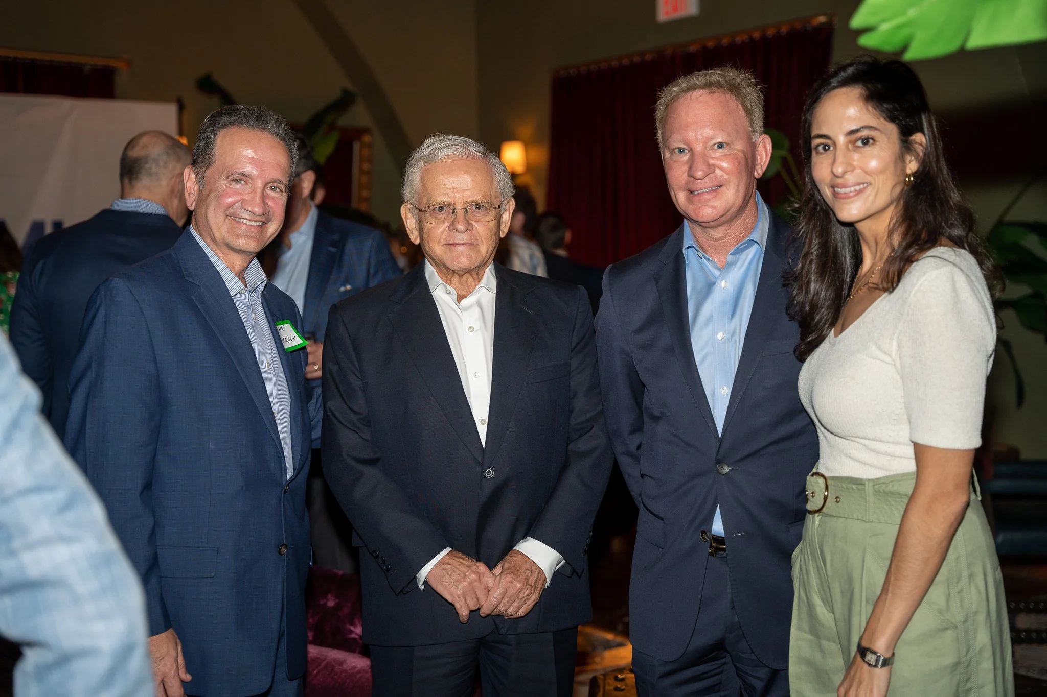 Four people in formal attire standing together at a social event, smiling for the camera.