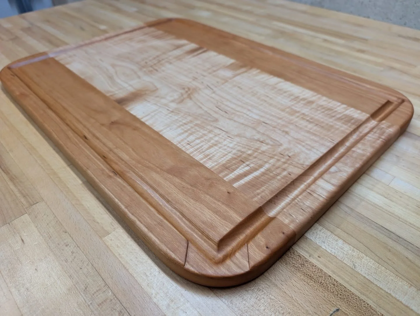 Maple &amp; Cherry Carving Board 🍁🍒🔪
.
Insanely curly Maple that pictures don't do justice to capture, with some supporting Cherry on the outsides to form a board big enough to carve a turkey on 🦃
The juice groove also features a pouring corner t