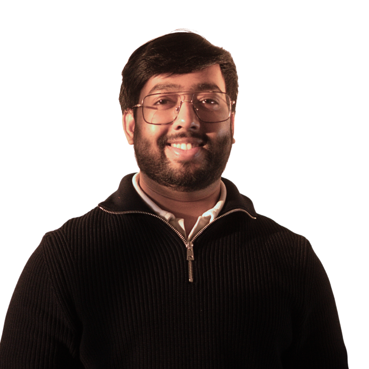 A man with black hair, wearing a blue sweater and beige pants, sitting on a bench with a neutral expression, casting a shadow on a plain, beige background.