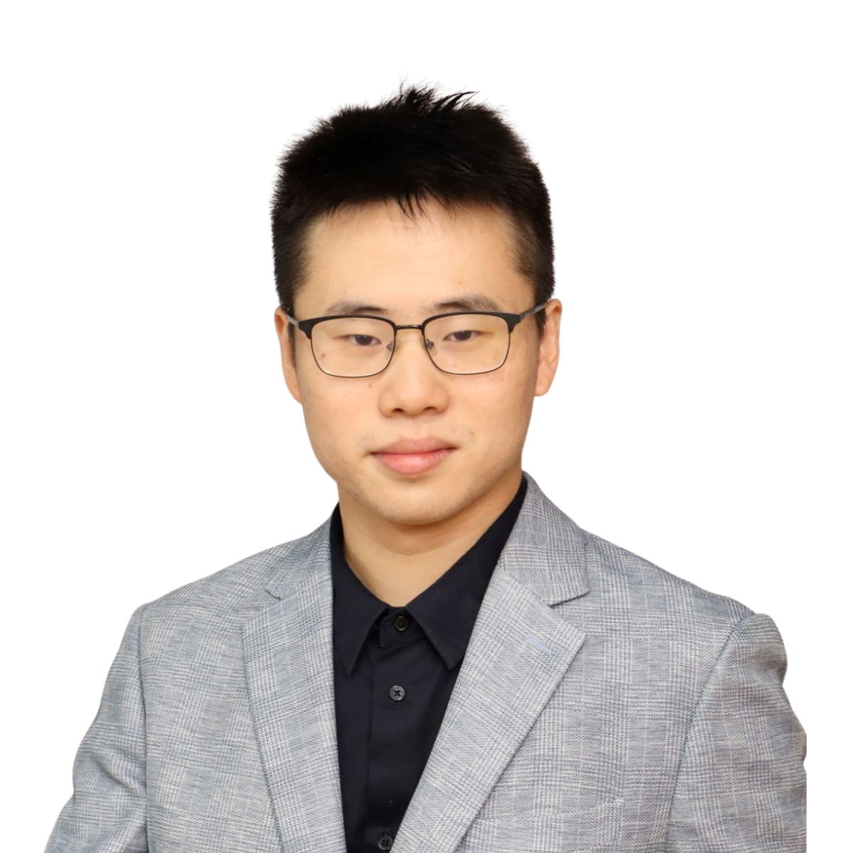 Professional portrait of a young man with short black hair, wearing glasses, a gray checkered blazer, and a black shirt, standing against a plain light-colored background.