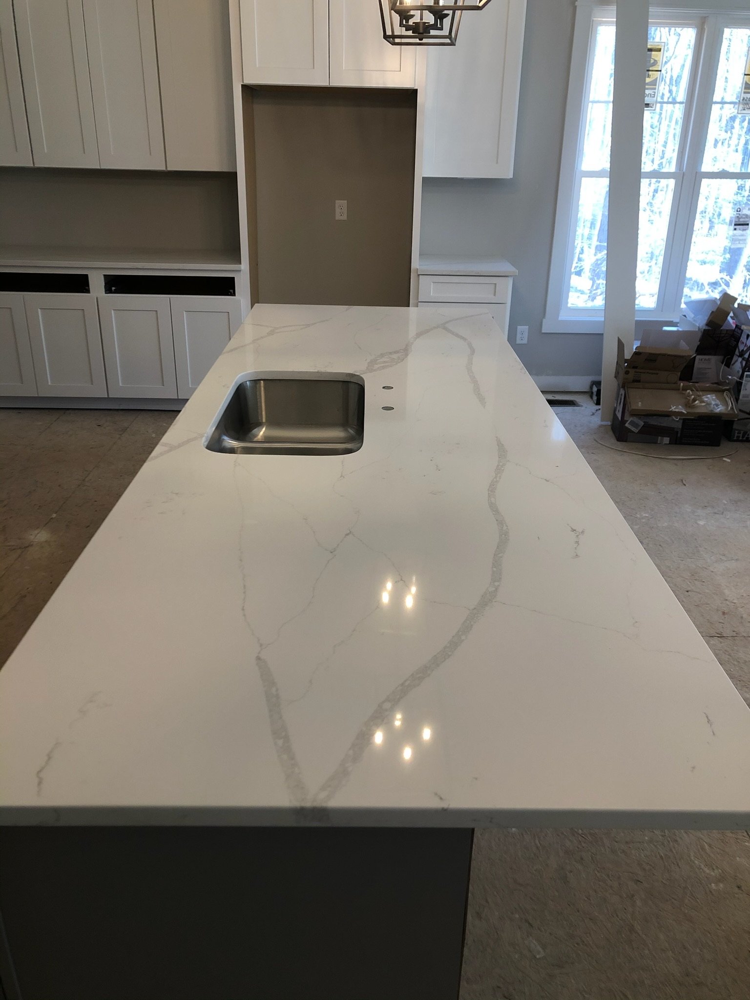 A kitchen island with a white marble countertop featuring grey veining, and a built-in stainless steel sink.