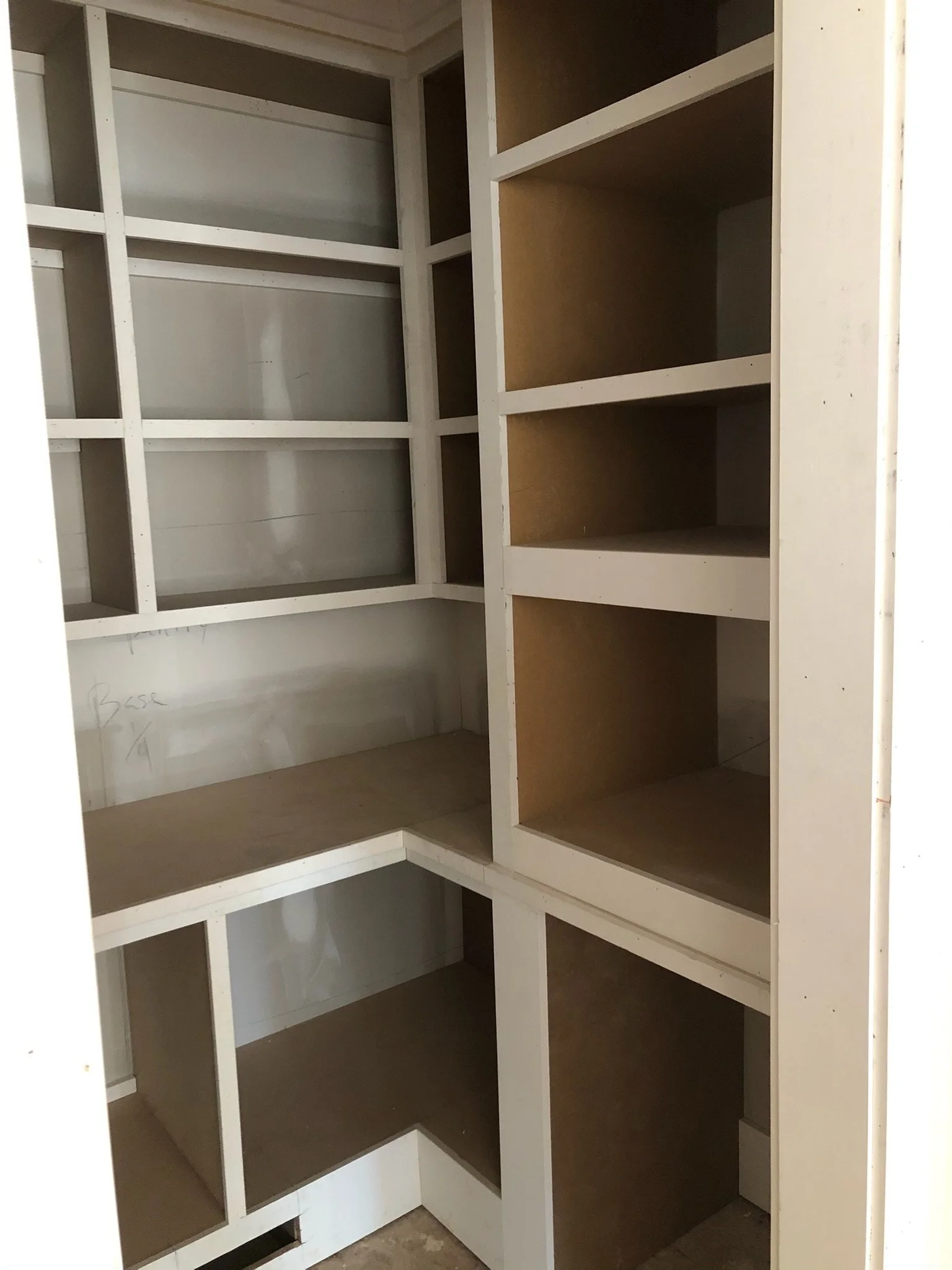 Empty white and brown wooden shelving unit in an unfinished space.