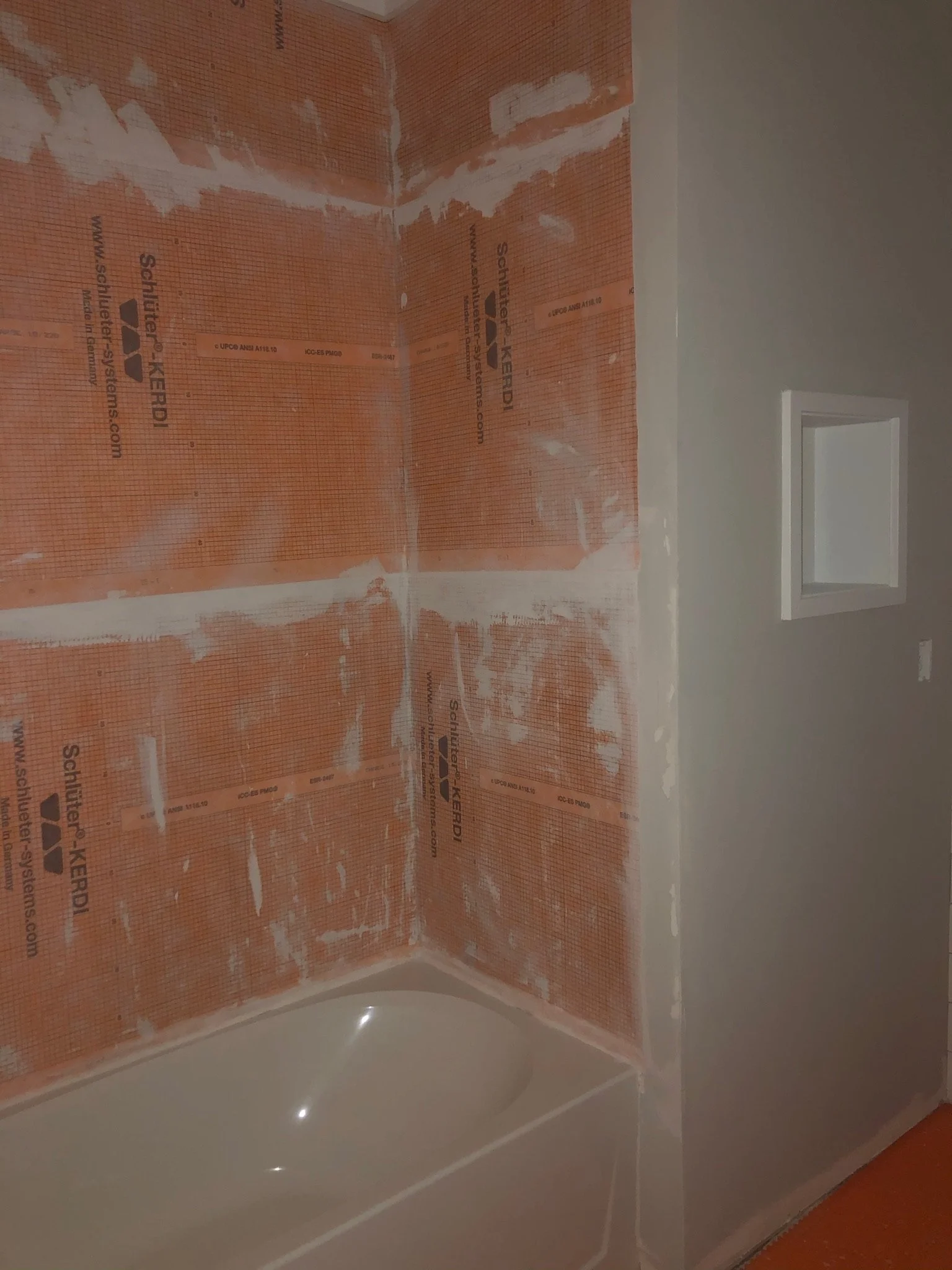 Bathroom with drywall and insulation installed on the wall, and a bathtub installed below.