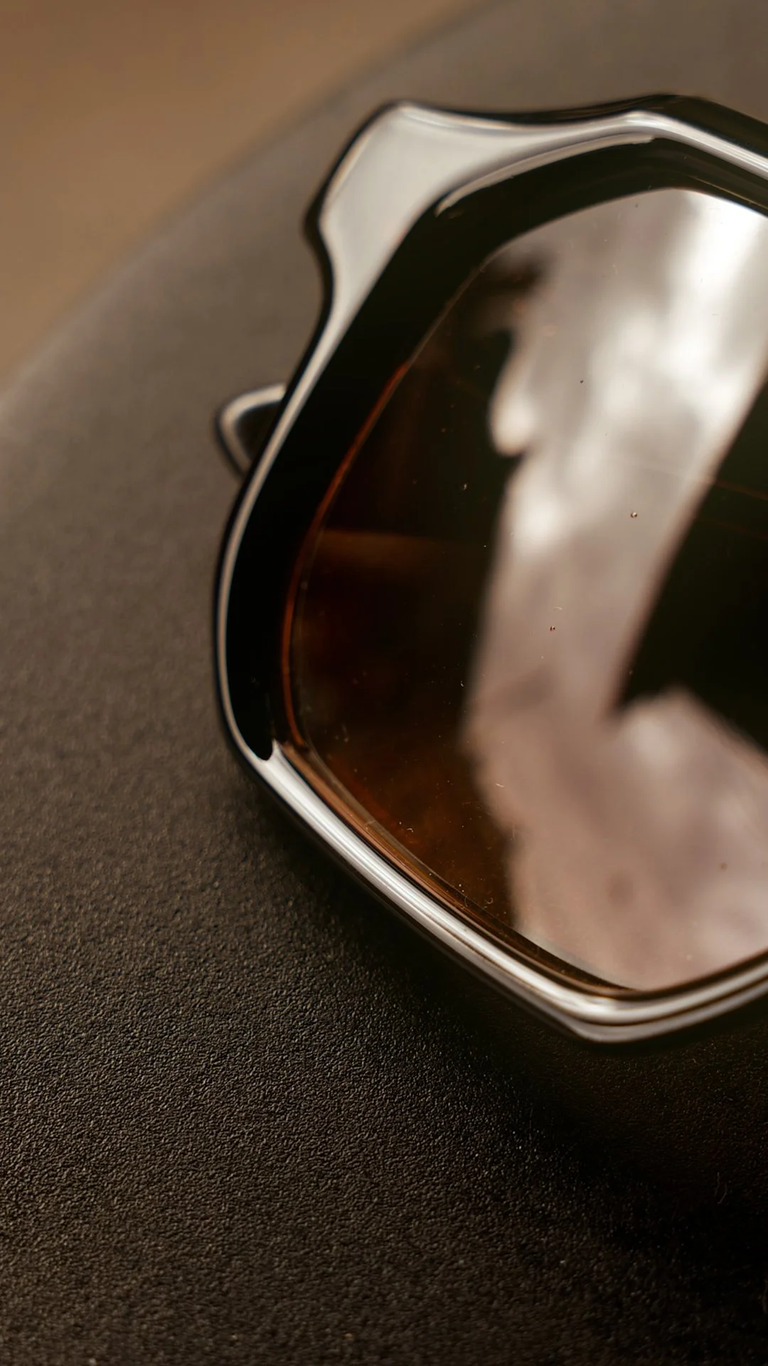 Close-up of HUG Spectacles DUPREE sunglasses, highlighting the sculptural black frame and tinted lens.