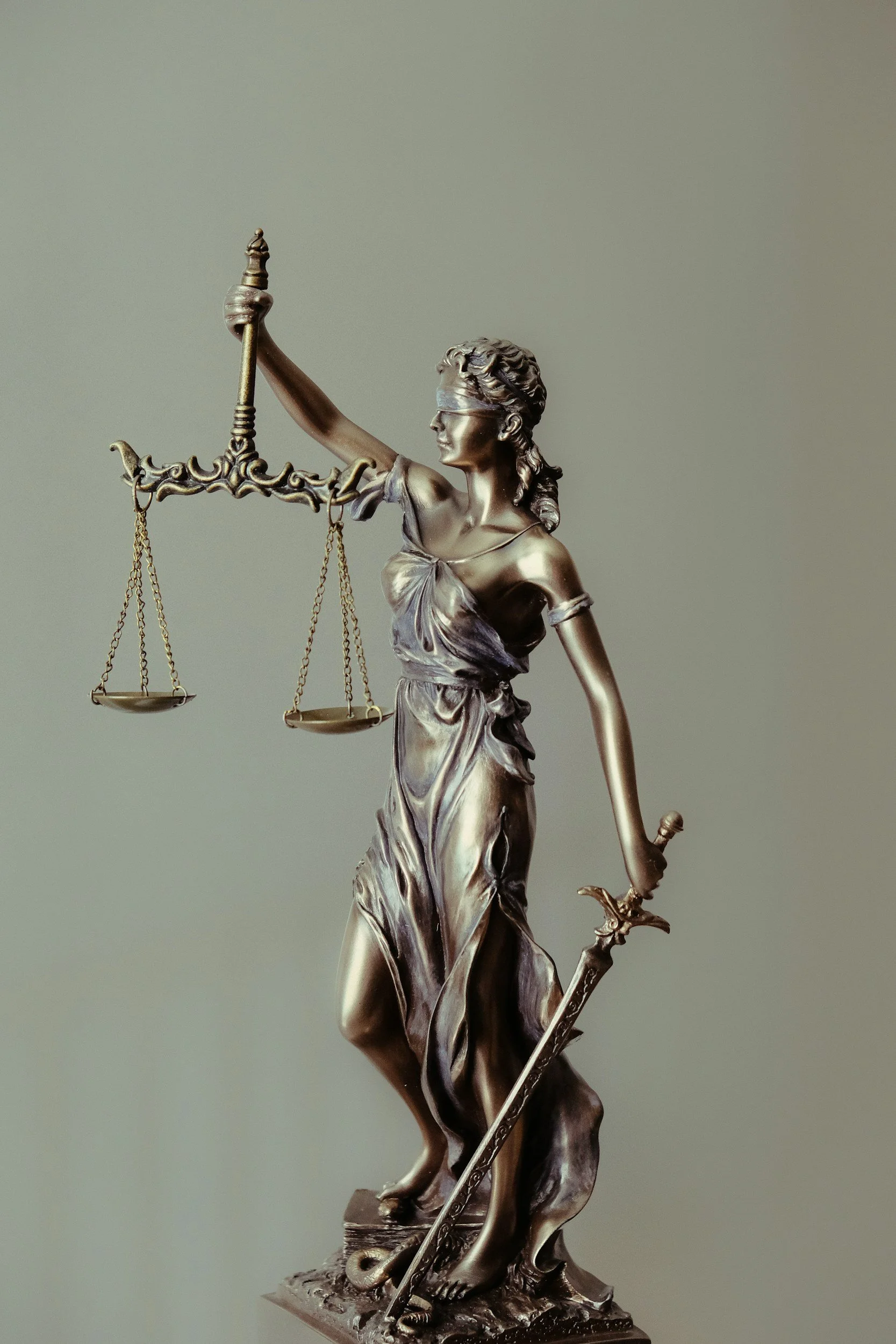 Bronze statue of Lady Justice holding a set of scales in her left hand and a sword in her right hand, with a blindfold covering her eyes.