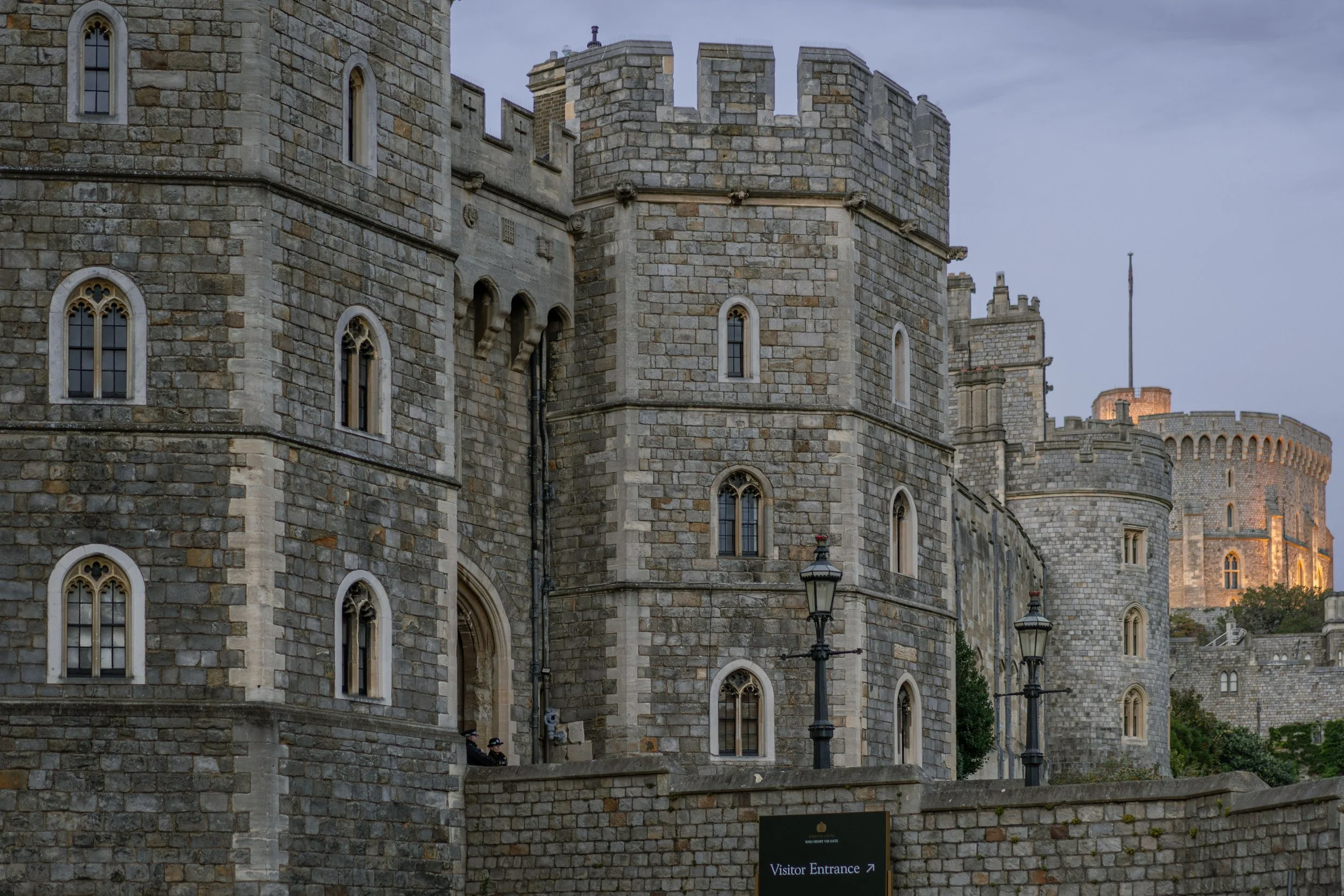 The historic stone fortresses and visitor entrance at Windsor Castle, highlighting the international cross-border connection.