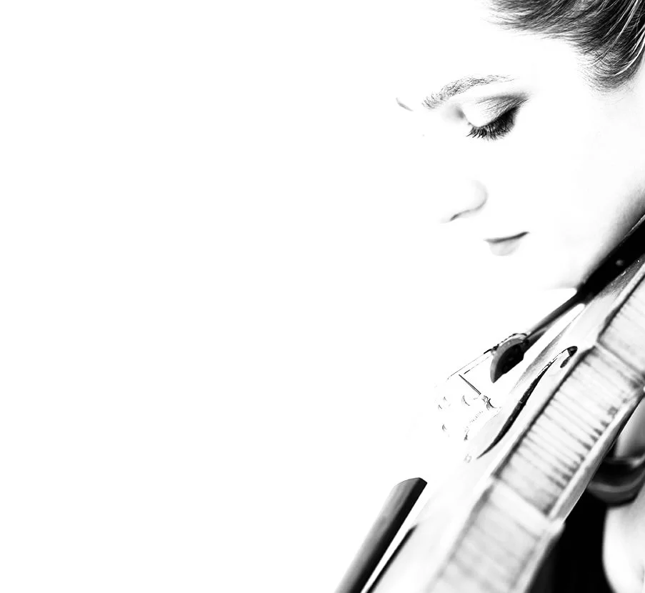 Close-up of a young girl's face in profile with closed eyes, holding a violin close to her face.