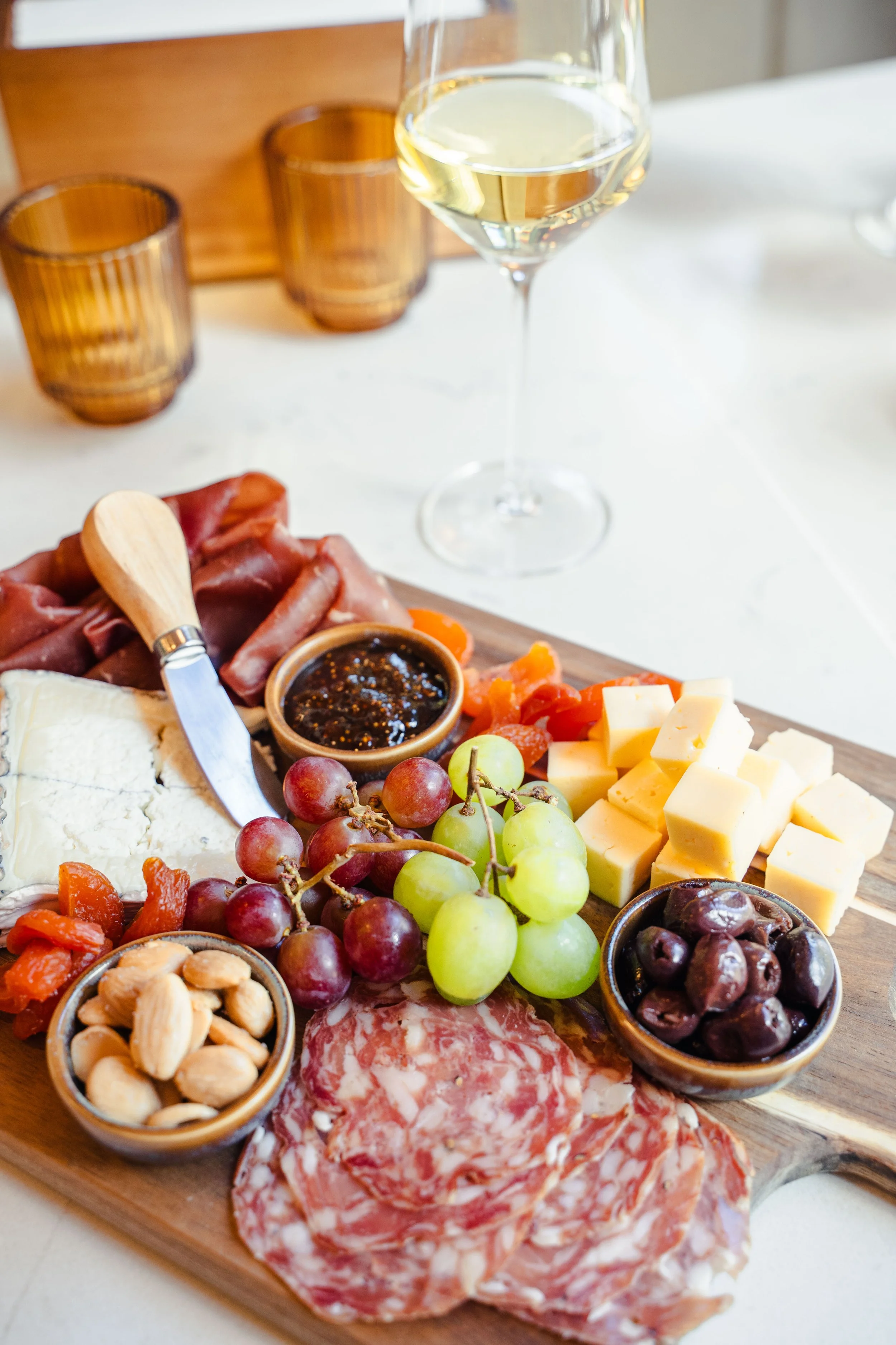 Gourmet charcuterie board with artisan cheeses, cured meats, and accompaniments paired with a glass of white wine at Eddy’s Kitchen in downtown Aspen.